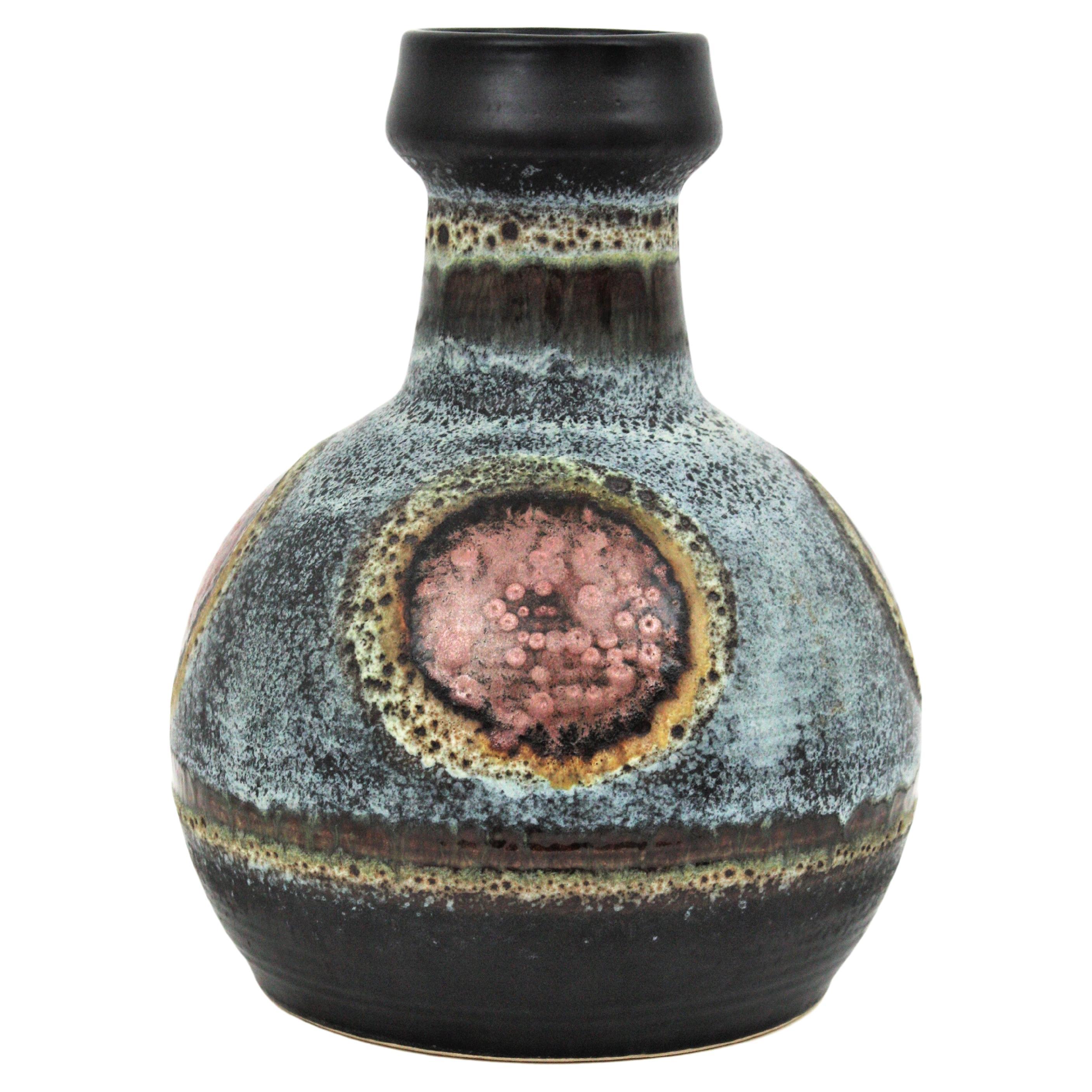 Beautiful ceramic bottle vase decorated with circles. Manufactured by Dümler and Breiden. Germany, 1950s.
This elegant pottery vase in brown and grey color is accented by abstract geometric decorations in copper color surrounded by shades of amber,