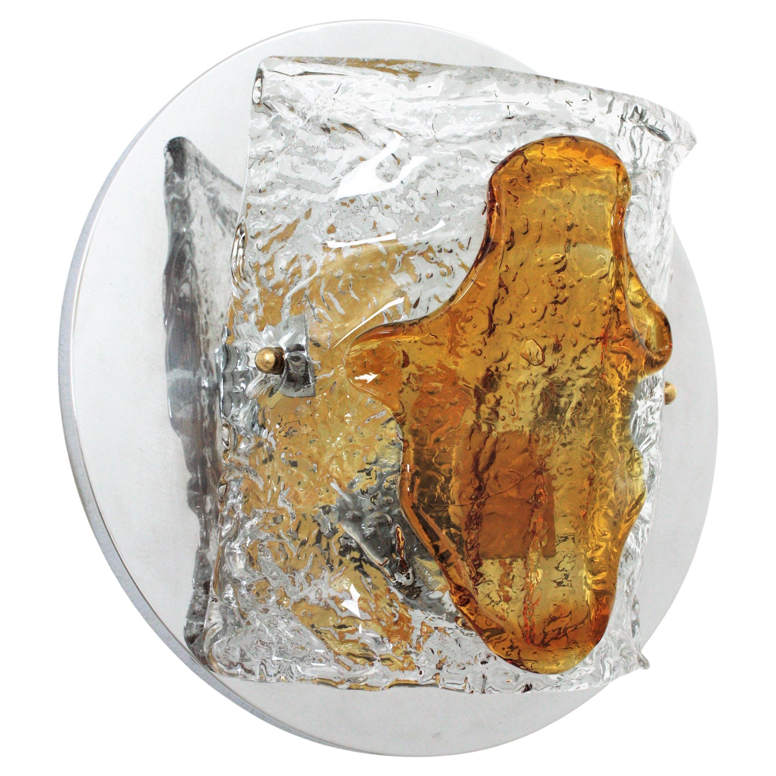 Elegant hand blown amber and clear Murano glass wall sconce by Mazzega, Italy, 1960s.
This beautiful wall light features a circular chromed steel backplate holding a half-cylinder glass shade in textured clear and amber glass.
This light fixture