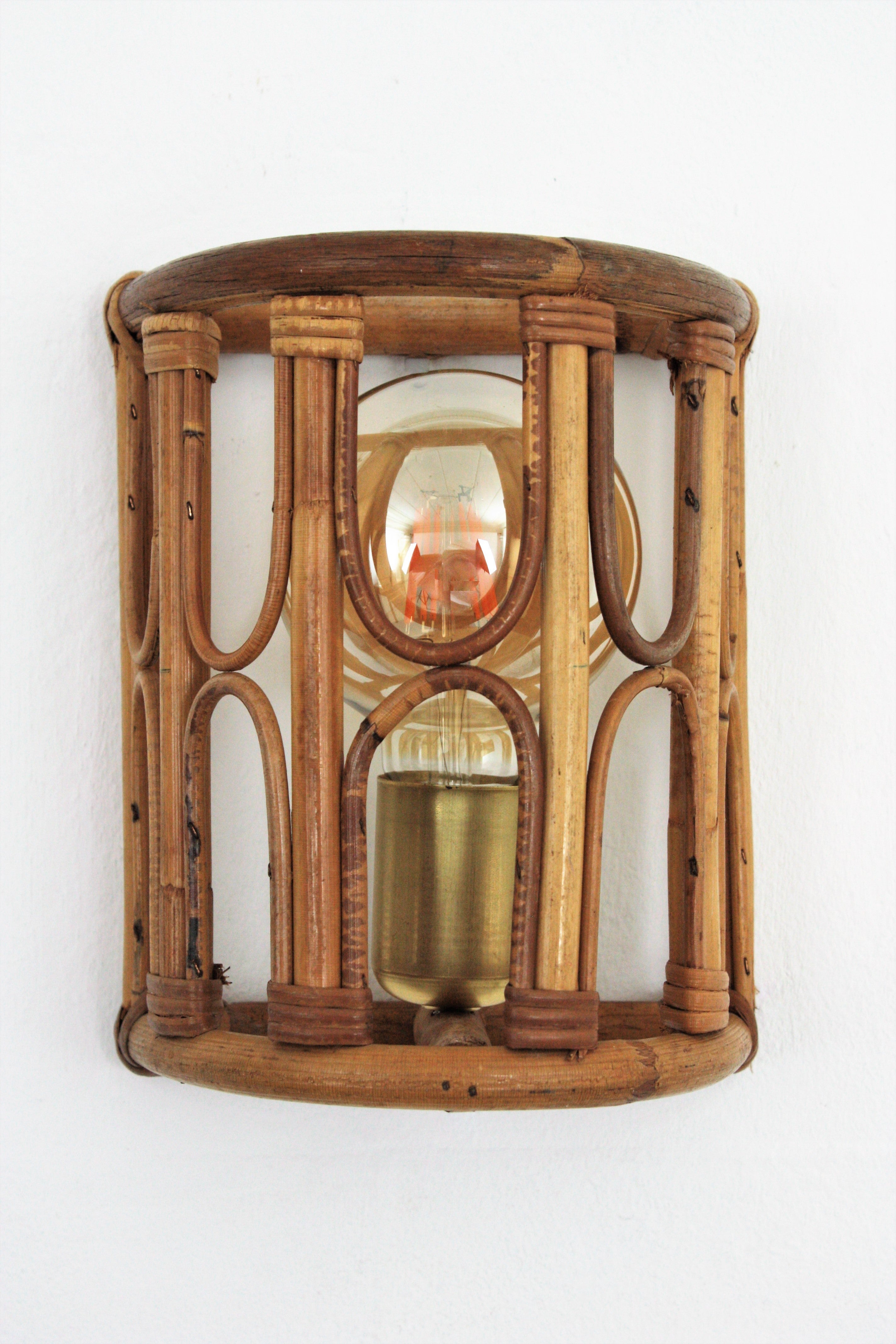 Belle applique demi-cylindre avec des abat-jour en bambou et rotin accentués par des décorations géométriques, Italie, années 1960.
Ce luminaire présente une structure semi-cylindrique en bambou ornée de détails en rotin. Il est doté d'un couvercle