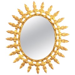 Espejo oval de metal dorado con motivos de flor de lis, España Años 50