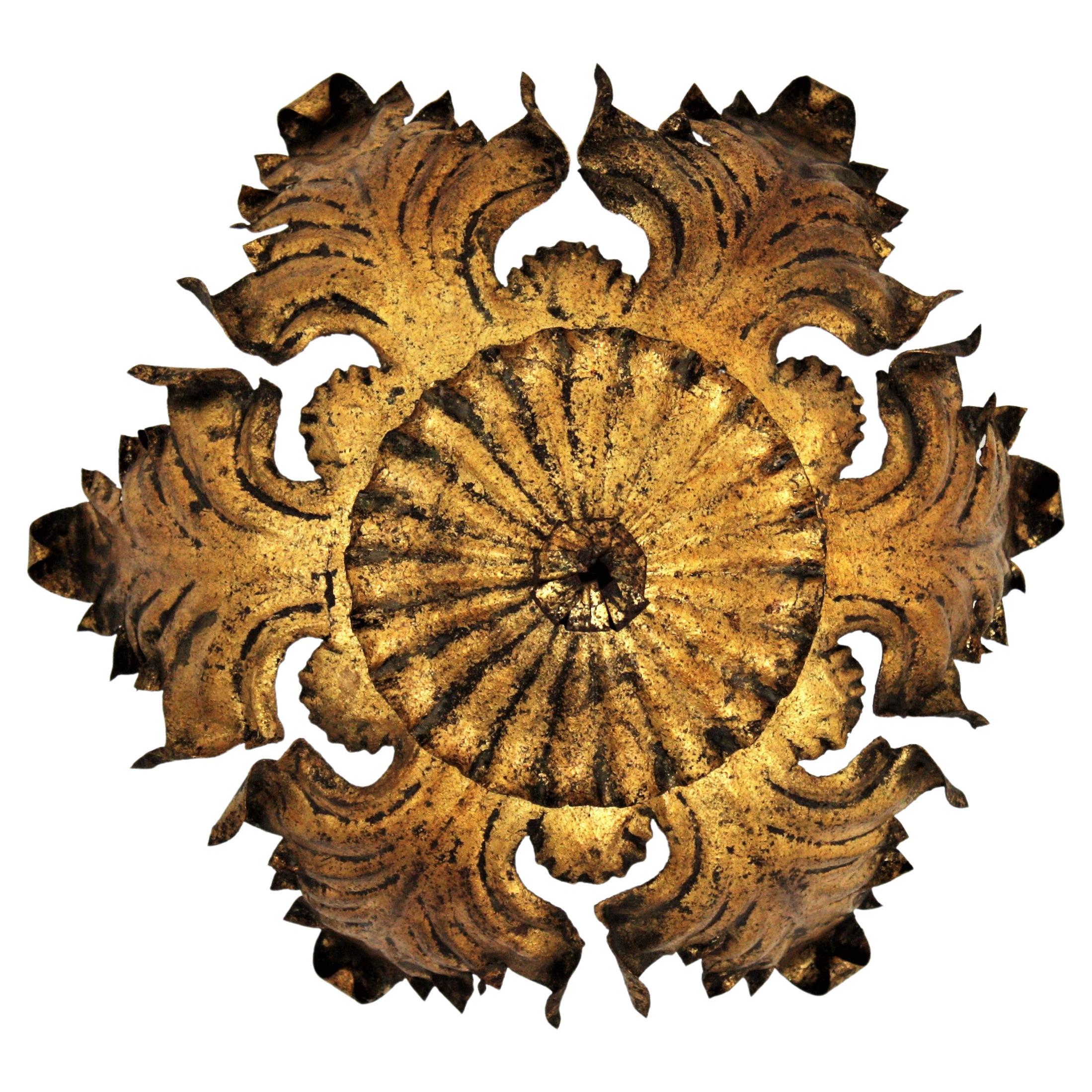Wrought iron gilt leafed sunburst ceiling light fixture or pendant, Italy, 1940s.
This sunburst light fixture features an ornamented leafed structure hanging from a stem ended by a canopy. It has heavily adorned and retains a nice aged patina with