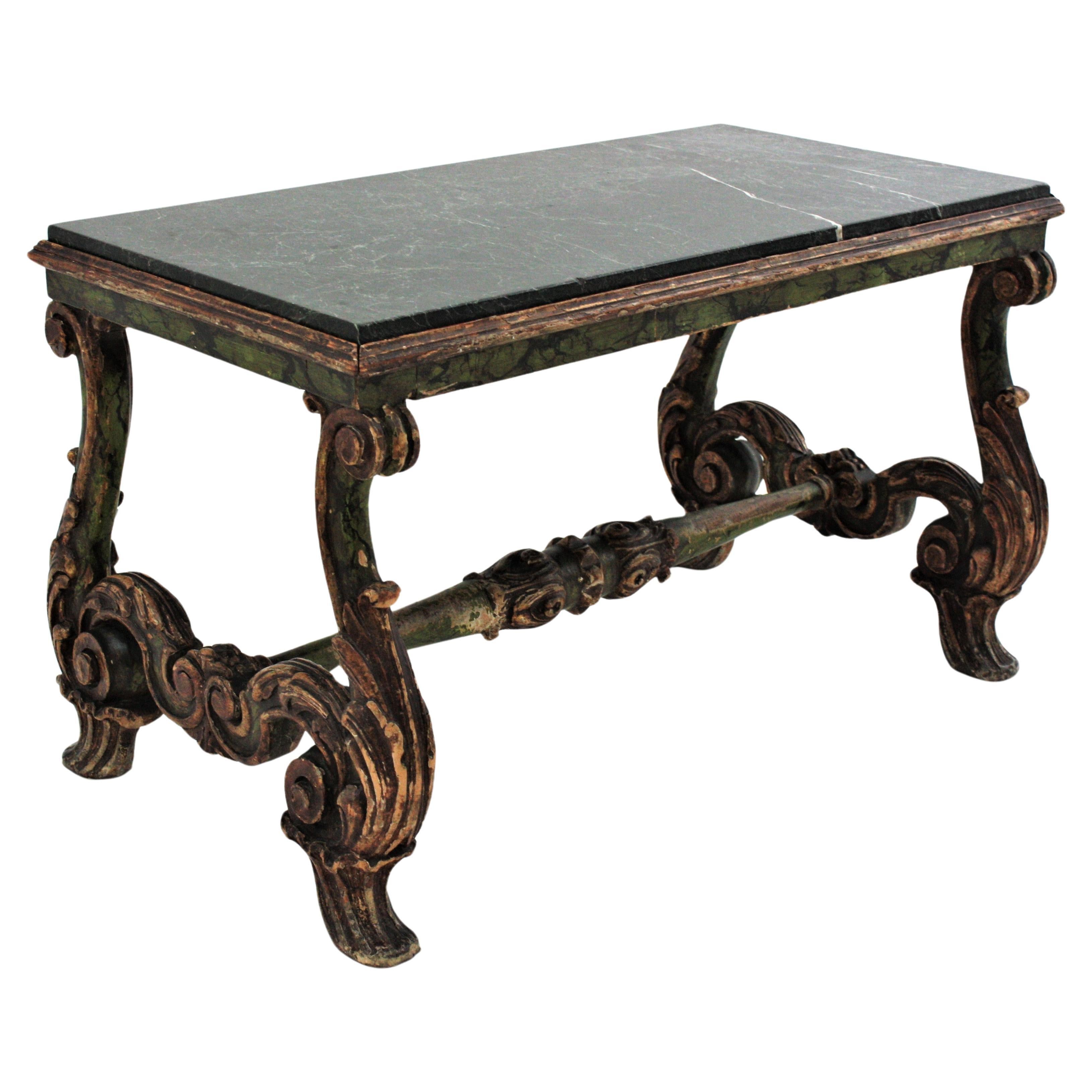 Elegant baroque style carved wood low table with dark green marble top. Spain, 19th century
The table stands up on two scrolled carved lyre legs adorned by acanthus leaves. They are connected by a carved wood stretcher. The marble top has beautiful