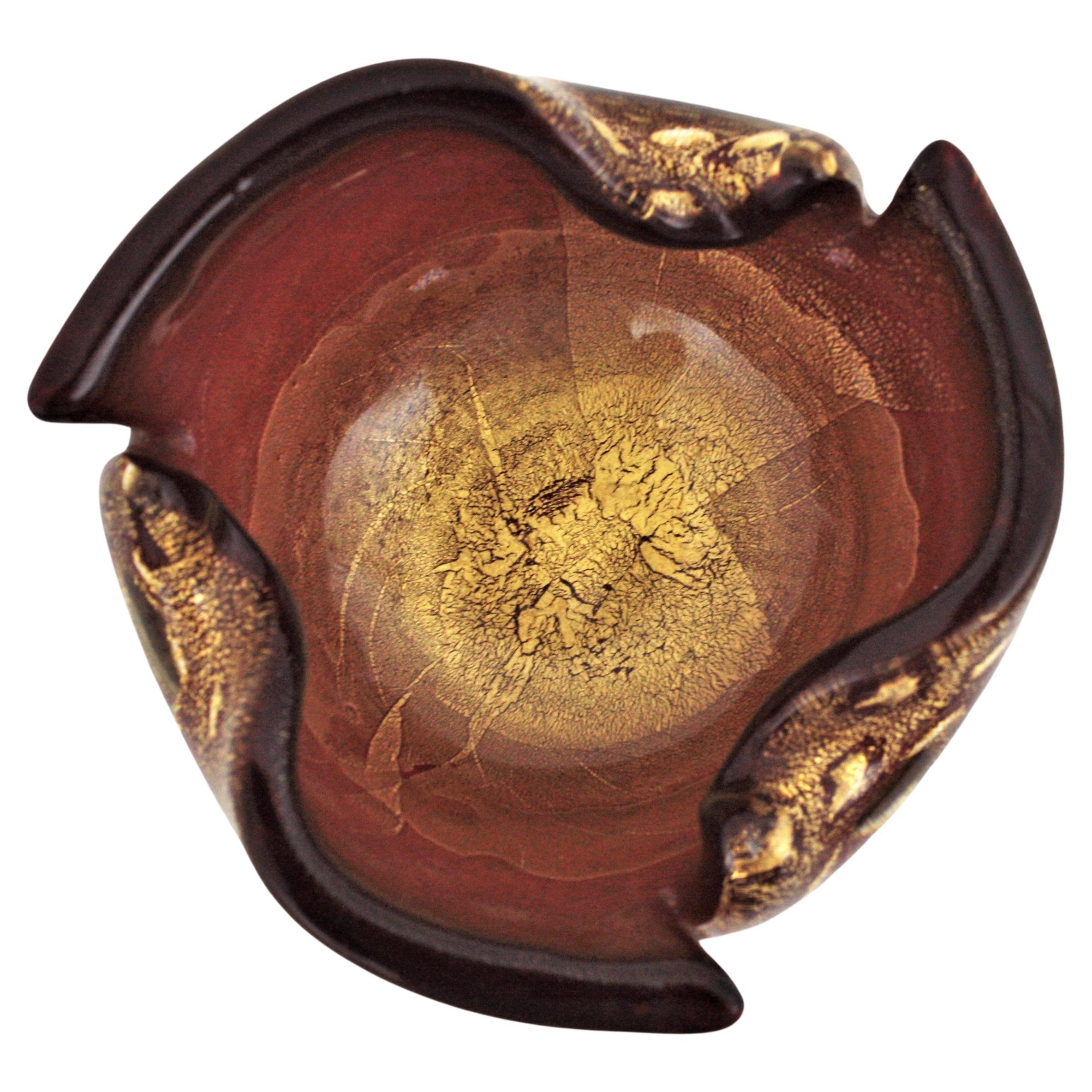 Eye-catching hand blown Murano cranberry red, gold flecks and controlled bubbles art glass bowl or ashtray. Attributed to Archimede Seguso, Italy, 1950s.
This stunning glass bowl has a freeform folded rim with air bubbles thorough and it is