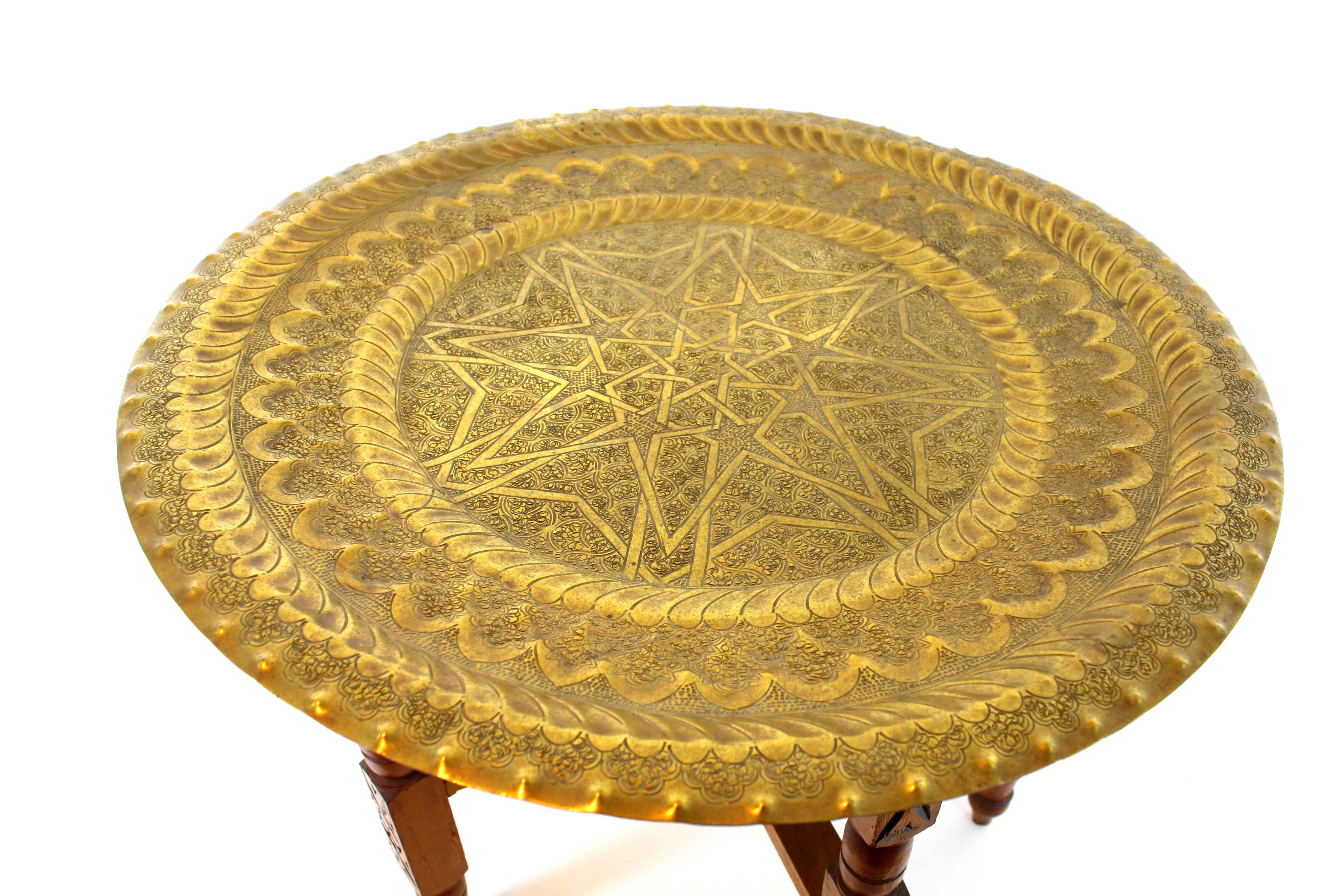 Large Traditional Moroccan Folding Tray Table, Brass, Wood, Morocco, 1940s-1950s.
This moorish brass tray table features a round brass tray with hand-hammered decorative details standing on a hand carved wood folding base.
To be used as coffee / tea