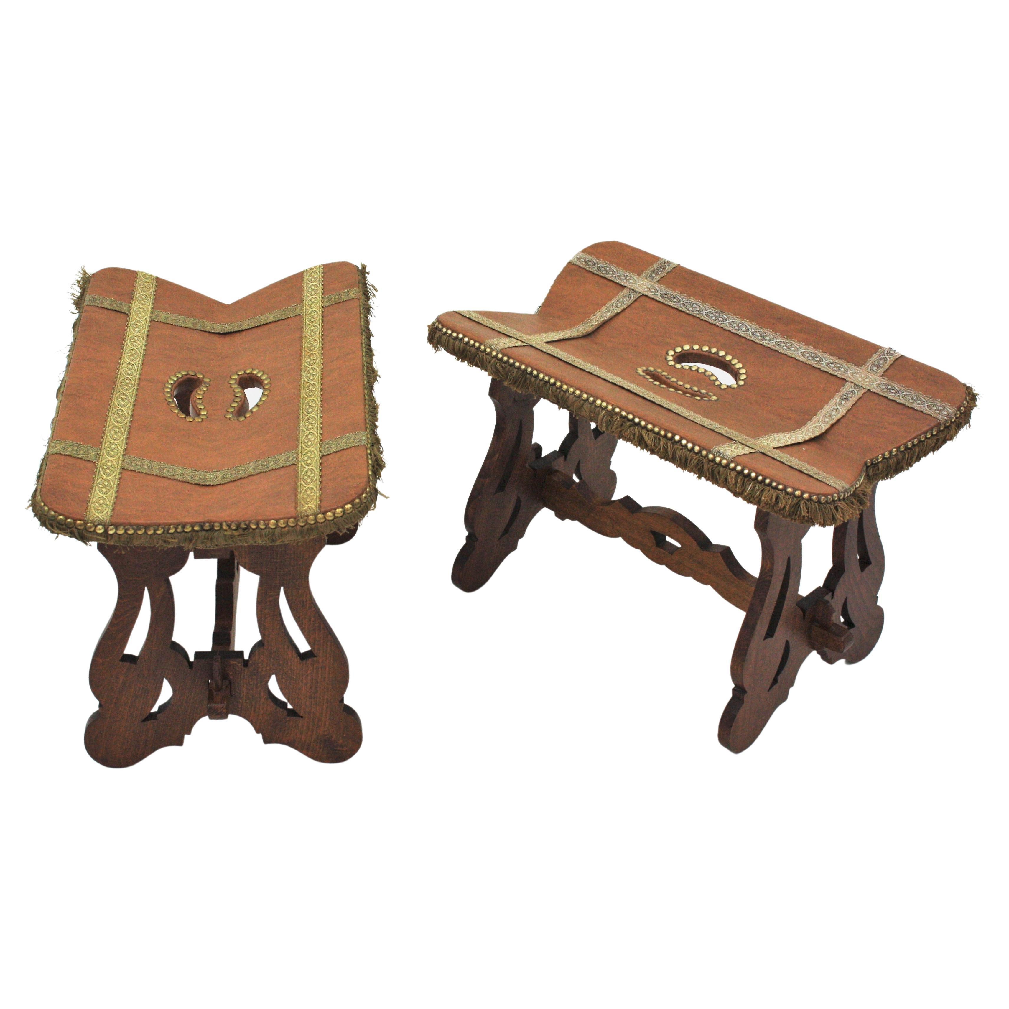 Beautiful pair of wooden Spanish colonial stools with trimming details. Spain, 1950s.
These stools are supported on trestle bases with lyre legs. The tops wear the original upholstery in brown leatherette with trimming details and fringed sides