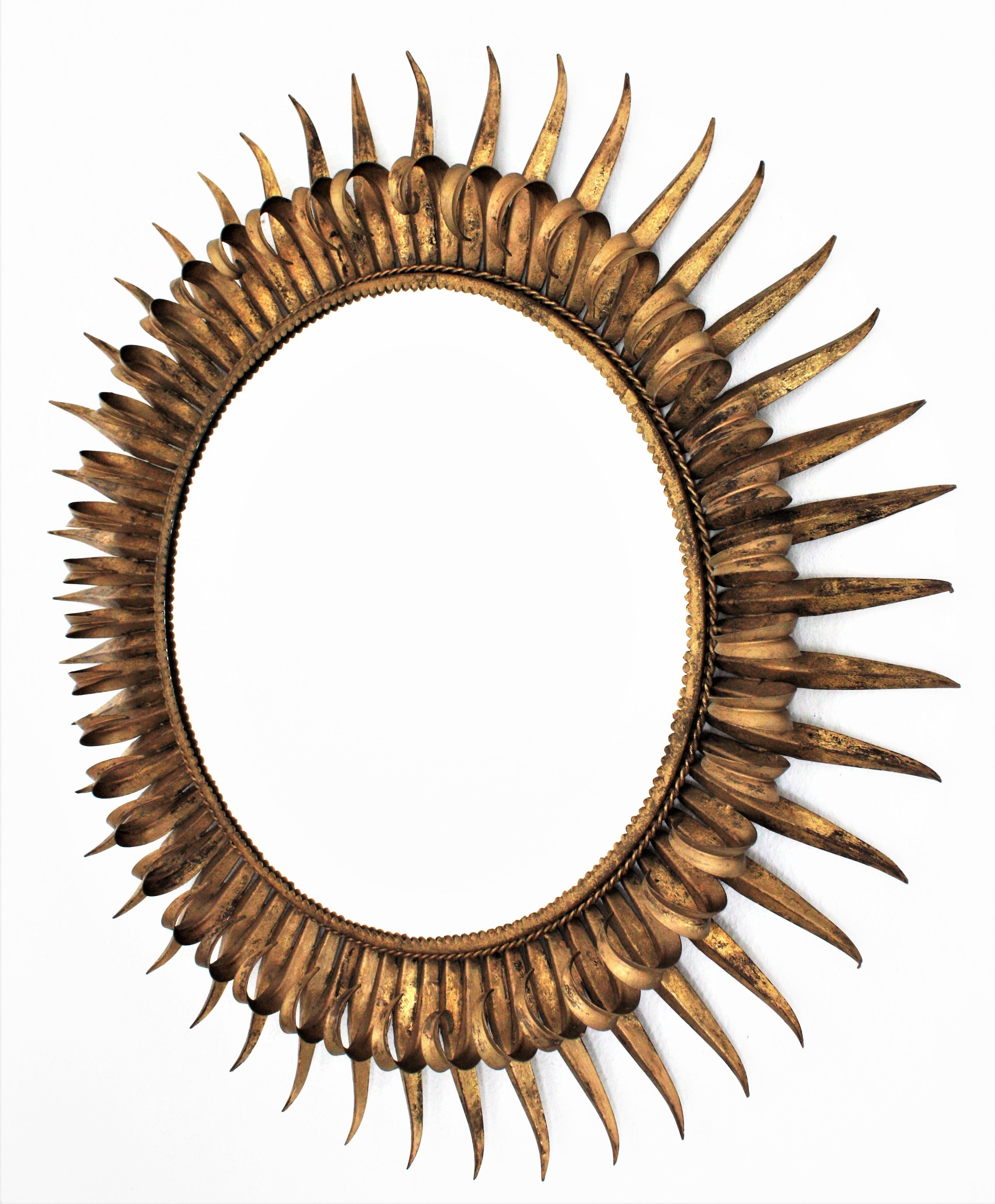 Large eyelash round sunburst mirror, gold gilt wrought iron, France, 1950s
Stunning large sized double layered eyelash gilt iron sunburst mirror with gold leaf finish. 
The frame is made by alternating hand-hammered curved and straight rays in