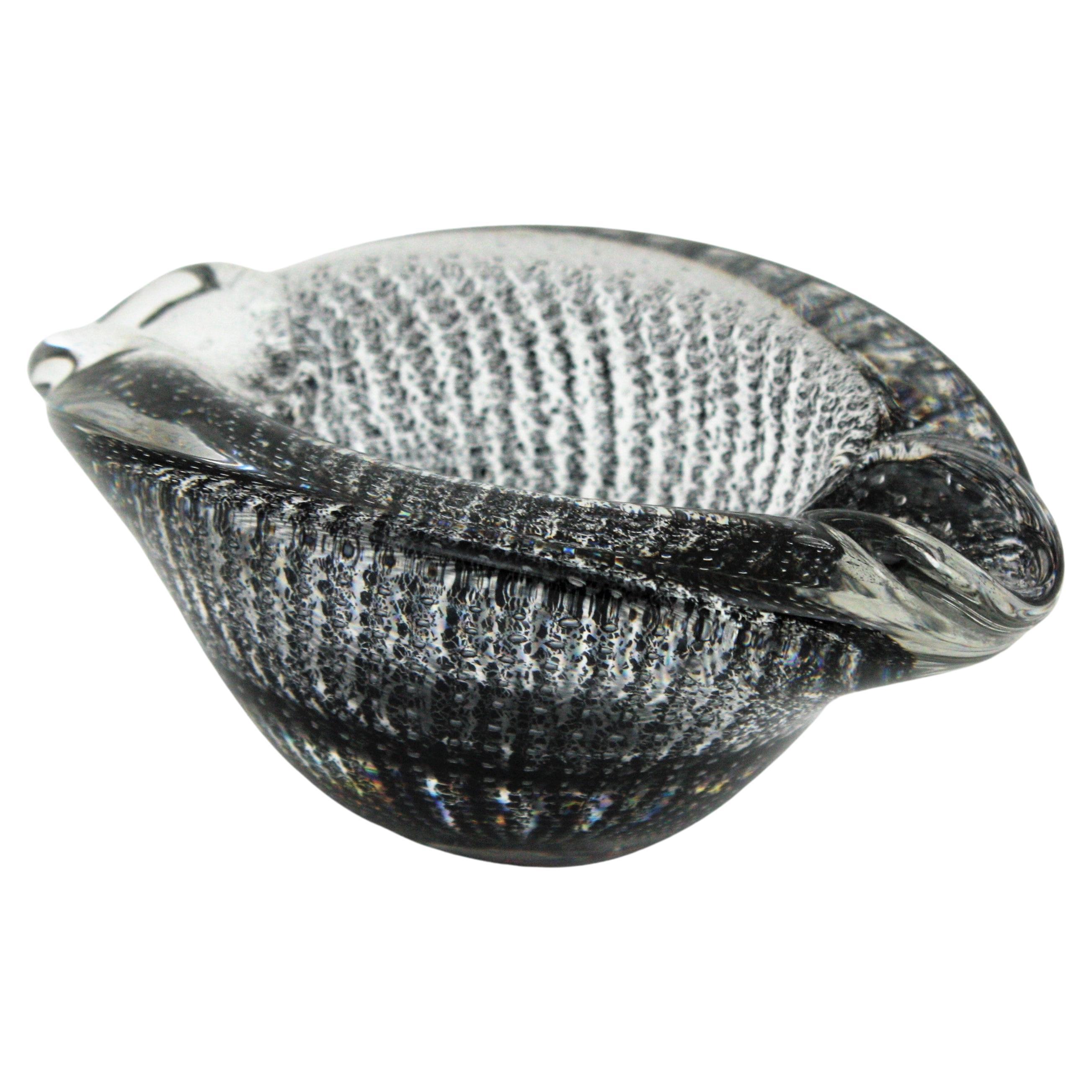 Striped Bullicante Murano clear glass ashtray with black inclusions. Attributed to Archimede Seguso. Italy, 1950s.
This eye-catching Murano glass bowl or ashtray is made in clear glass with black flecks and controlled air bubbles. The black