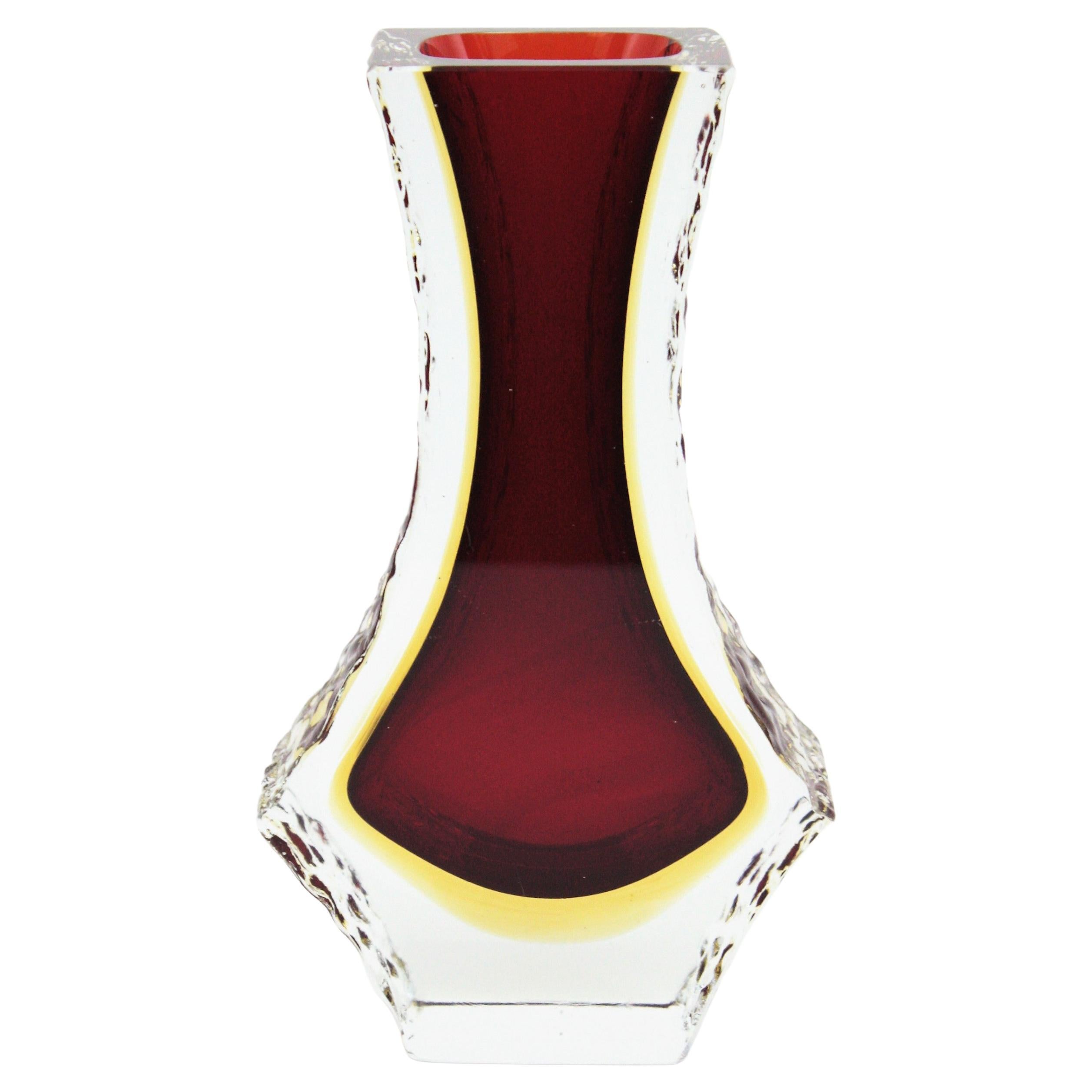Vase aus facettiertem Muranoglas aus der Jahrhundertmitte mit strukturierten Eisglasrändern. Zuschreibung an Mandruzzato, Italien, 1960er Jahre.
Sommerso-Technik mit rotem Glas und einer gelben Schicht, die in klares Glas getaucht ist.
Sehr