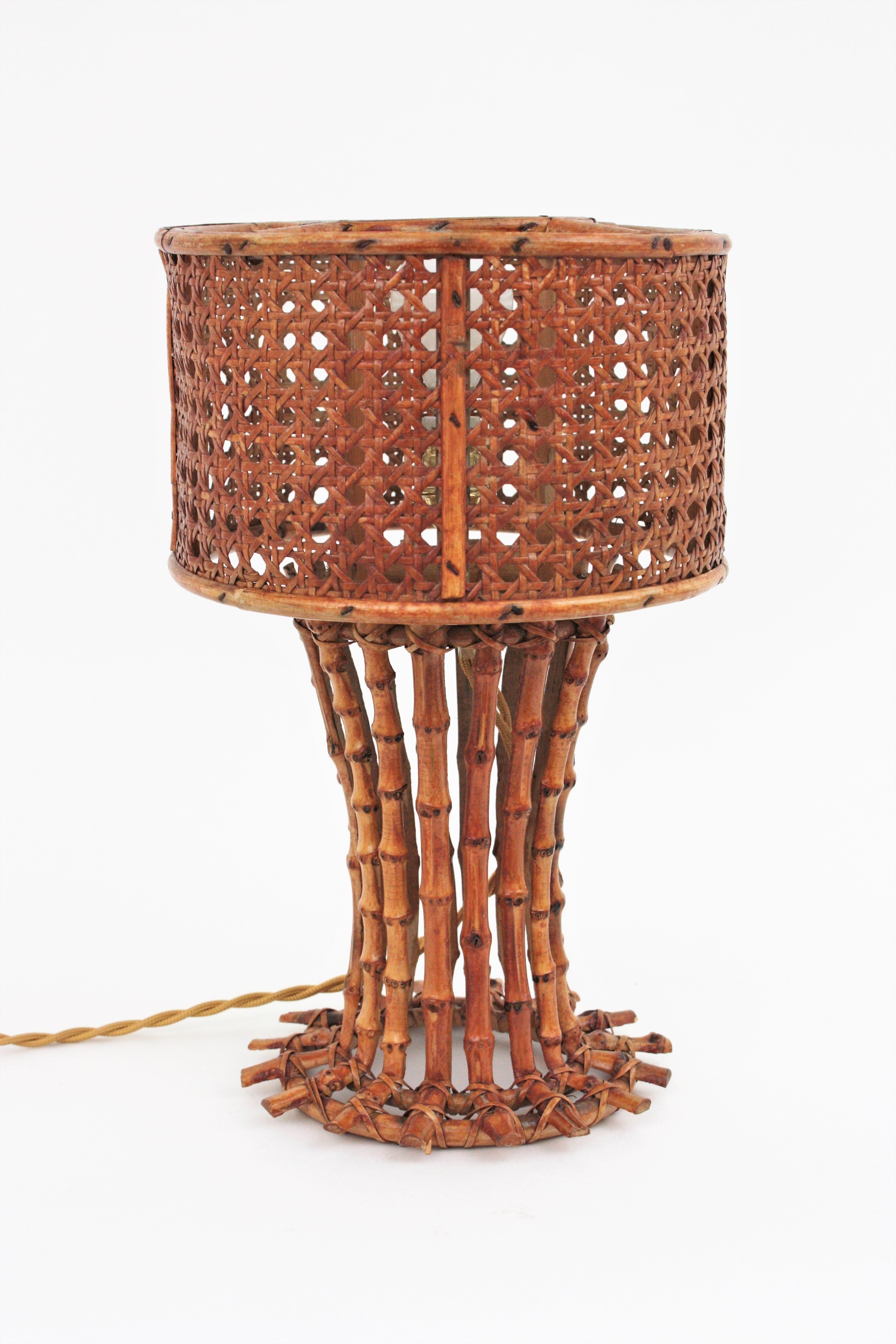 Eyecatching bamboo and rattan table lamp with woven wicker wire shade, Italy, 1950s-1960s.
This lovely table lamp features a bamboo cane structure holding a wicker weave cylinder shade. 
Handcrafted in Italy at the mid-20th century period it