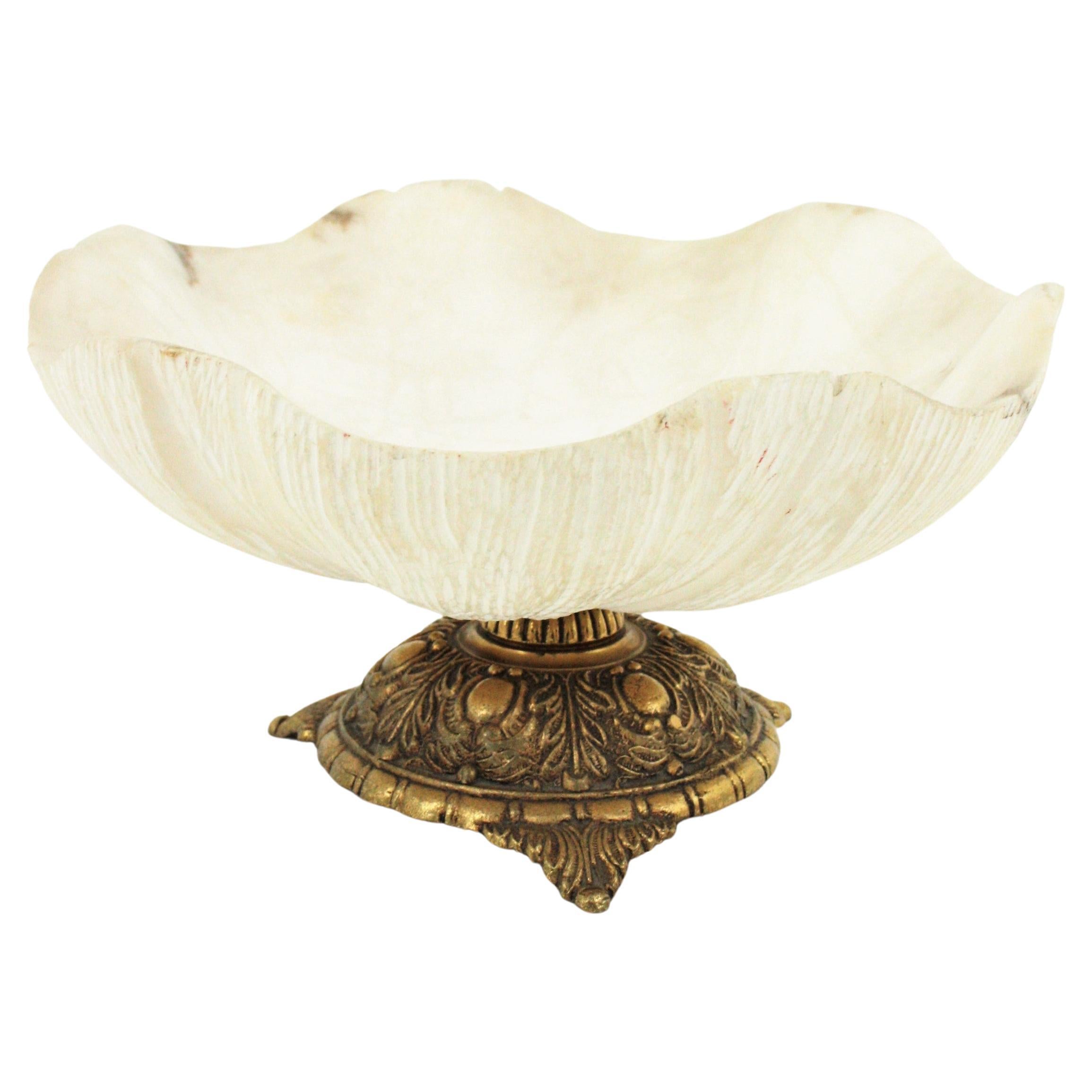 Outstanding centerpiece or footed bowl in carved alabaster and bronze. France, 1930s.
This carved alabaster centerpiece bowl stands up on a bronze base adorned with foliage details.
The alabaster surface has stripped carved decorations underneath