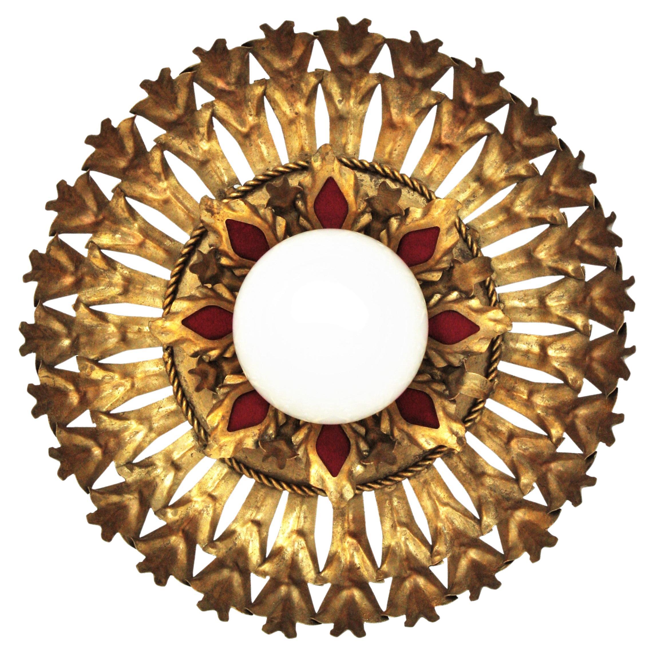 Eye catching sunburst light fixture with foliage design and milk glass globe shade, Spain, 1950s
This ceiling flush mount has two layers of leaves in gilt iron surrounding a central opaline glass globe shaped shade. It has decorative details in red