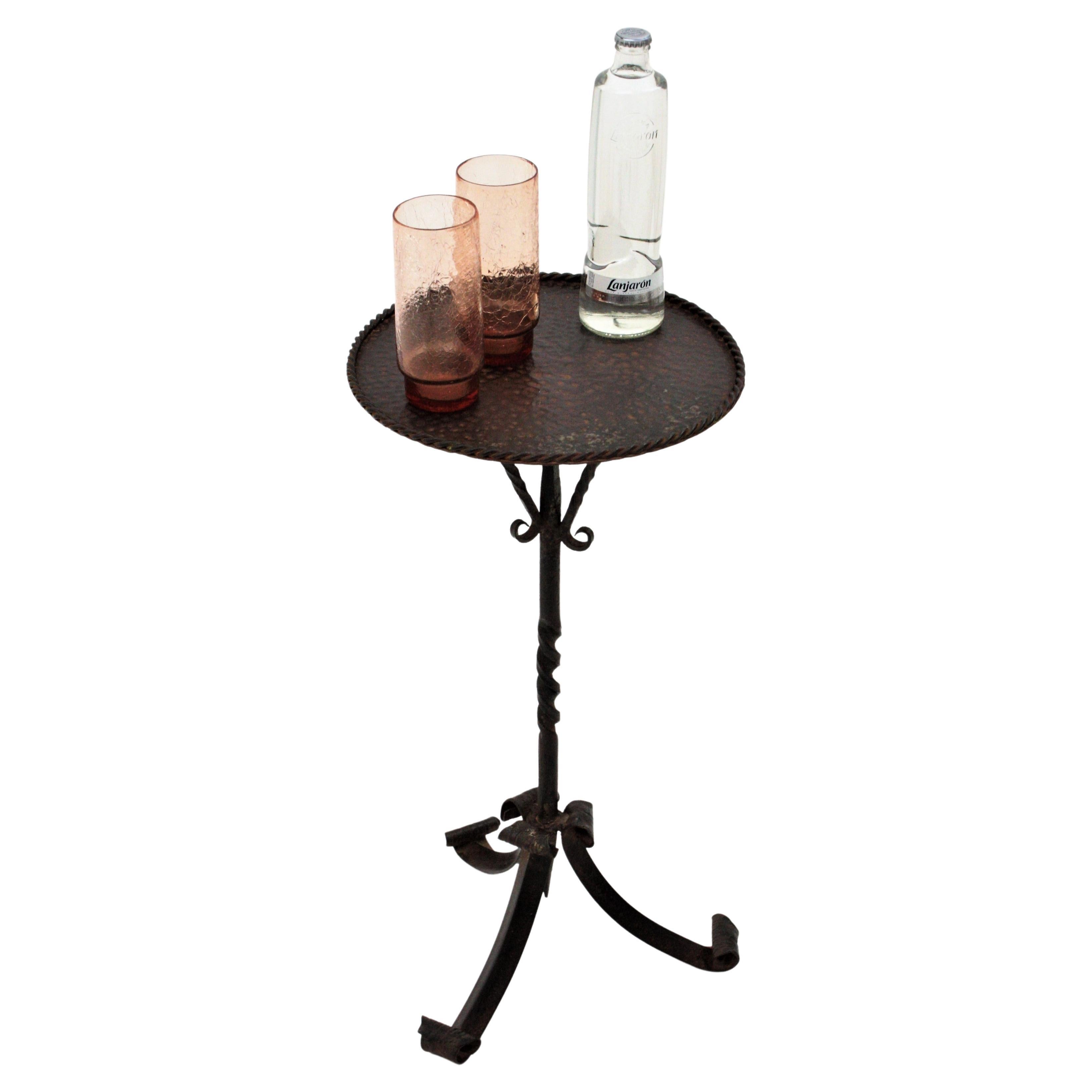 Spanish wrought iron gueridon end table / cocktails table standing on a tripod base, Spain, 1950s.
Handcrafted in wrought iron. The top of this pedestal is heavily adorned by the hammer marks. It stands up on a tripod base with decorative details on