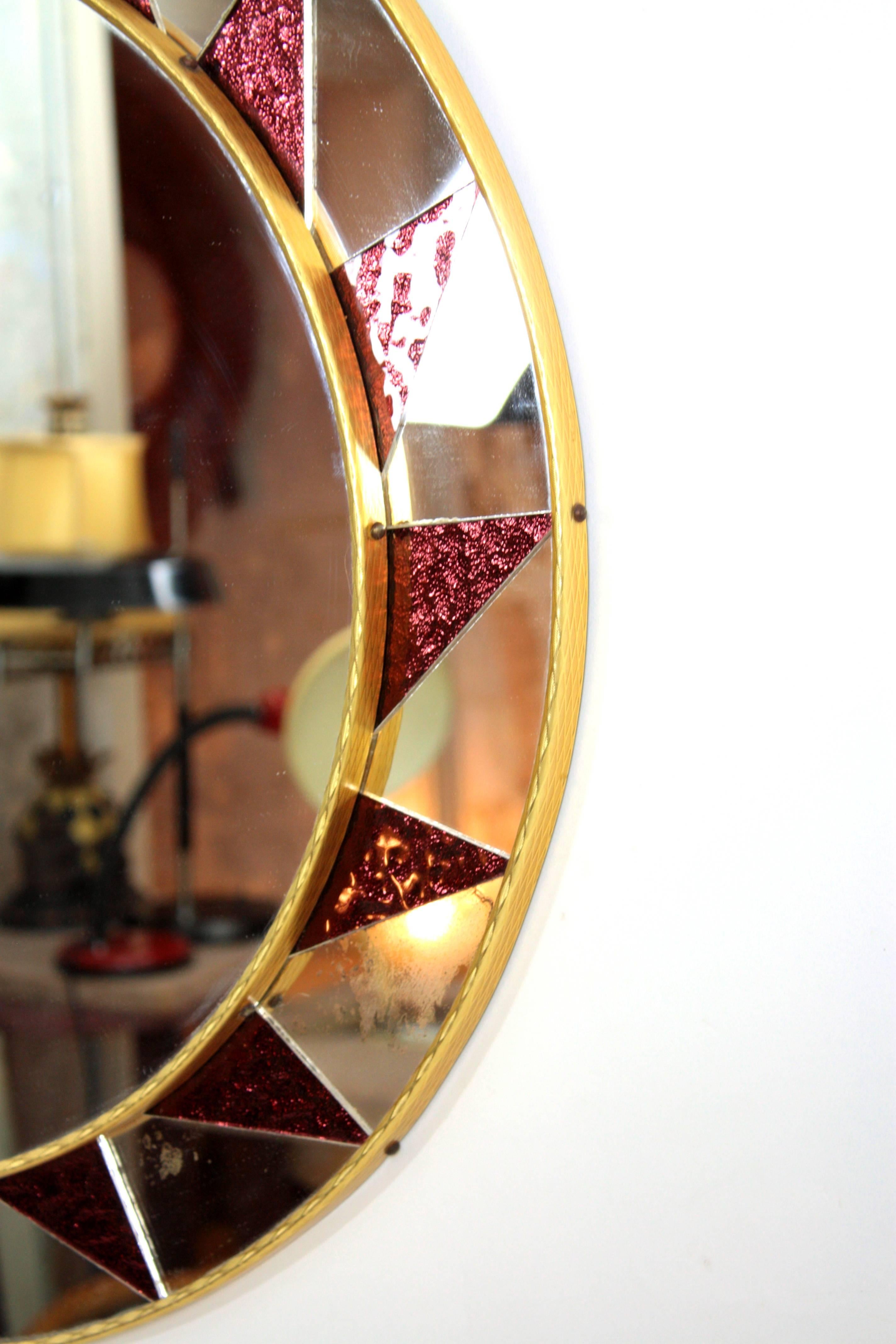 Miroir solaire circulaire espagnol du milieu du siècle dernier avec des verres irisés en grenat.
Miroir central rond encadré par un étonnant motif de miroirs et de pièces de grenat colorées  de verre.
Espagne, années 1960
