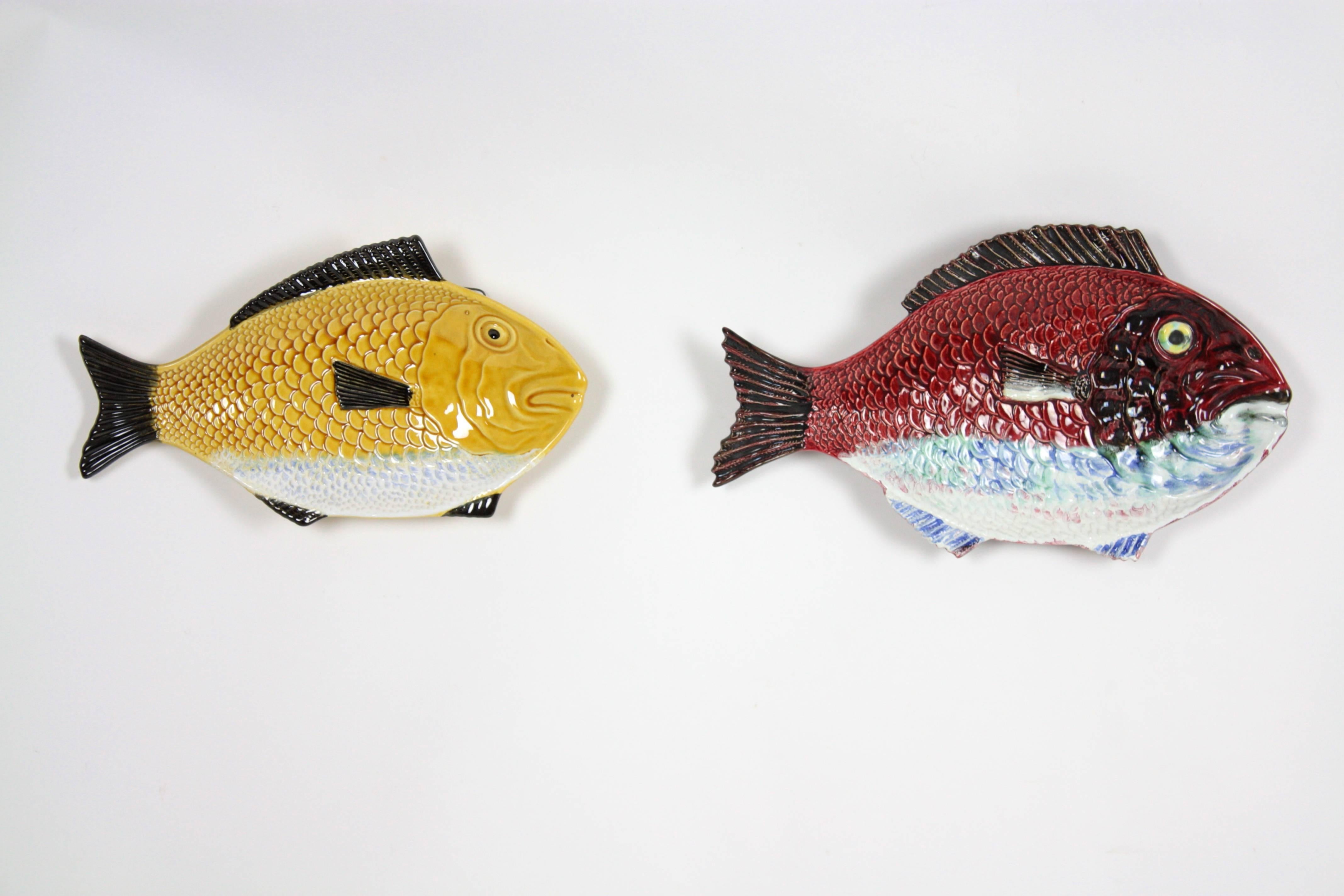 A pair of Portuguese glazed ceramic fish platters with vibrant red and yellow colors. Beautiful to use as a wall decoration. 

The fish plates are in perfect condition. One on them signed 