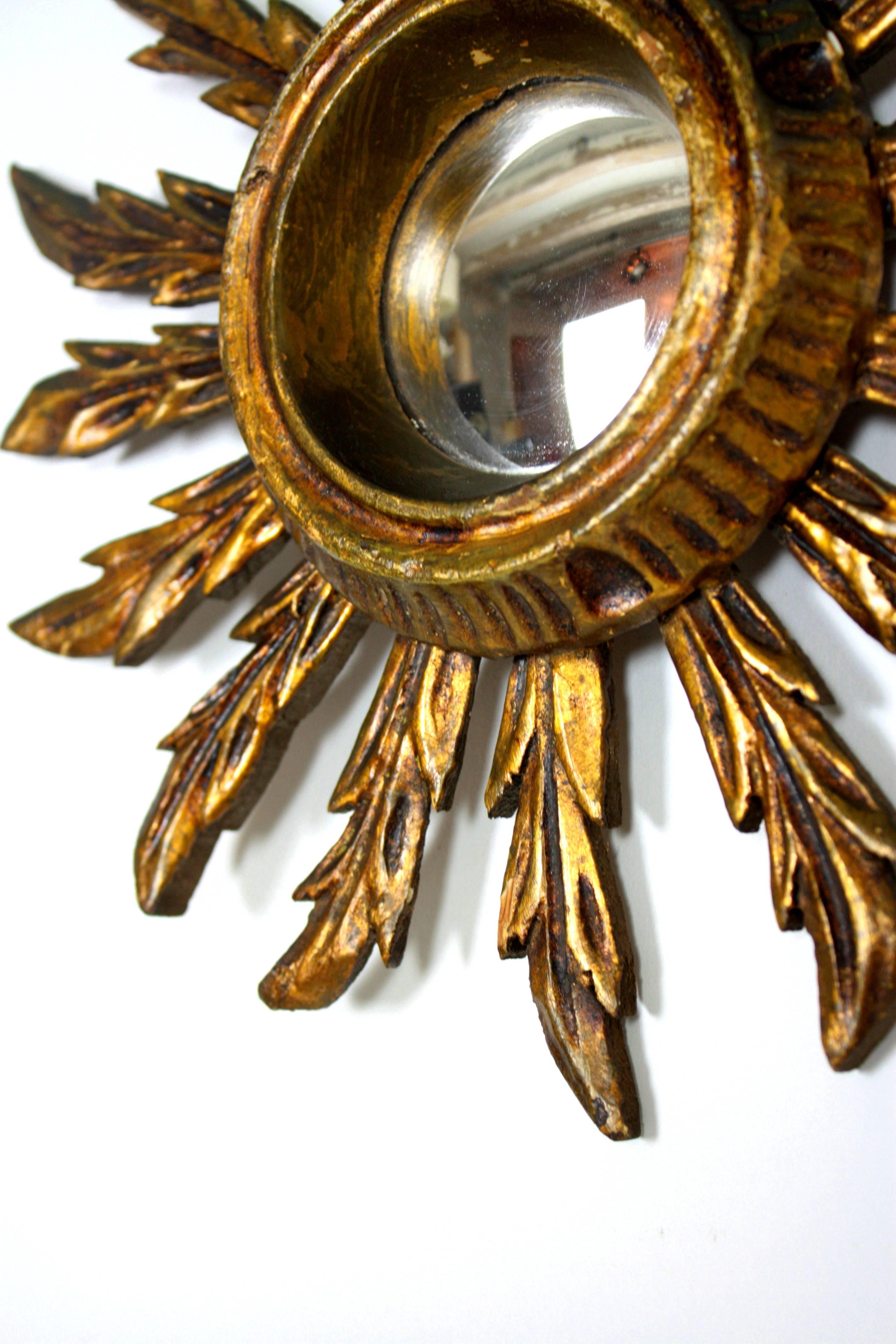 Beautiful pair of sunburst mirrors in a rare mini size. Carved wood covered with ghesso and gold leave finish.

Lovely vintage patina. Both of them wear the original convex glass mirror.
