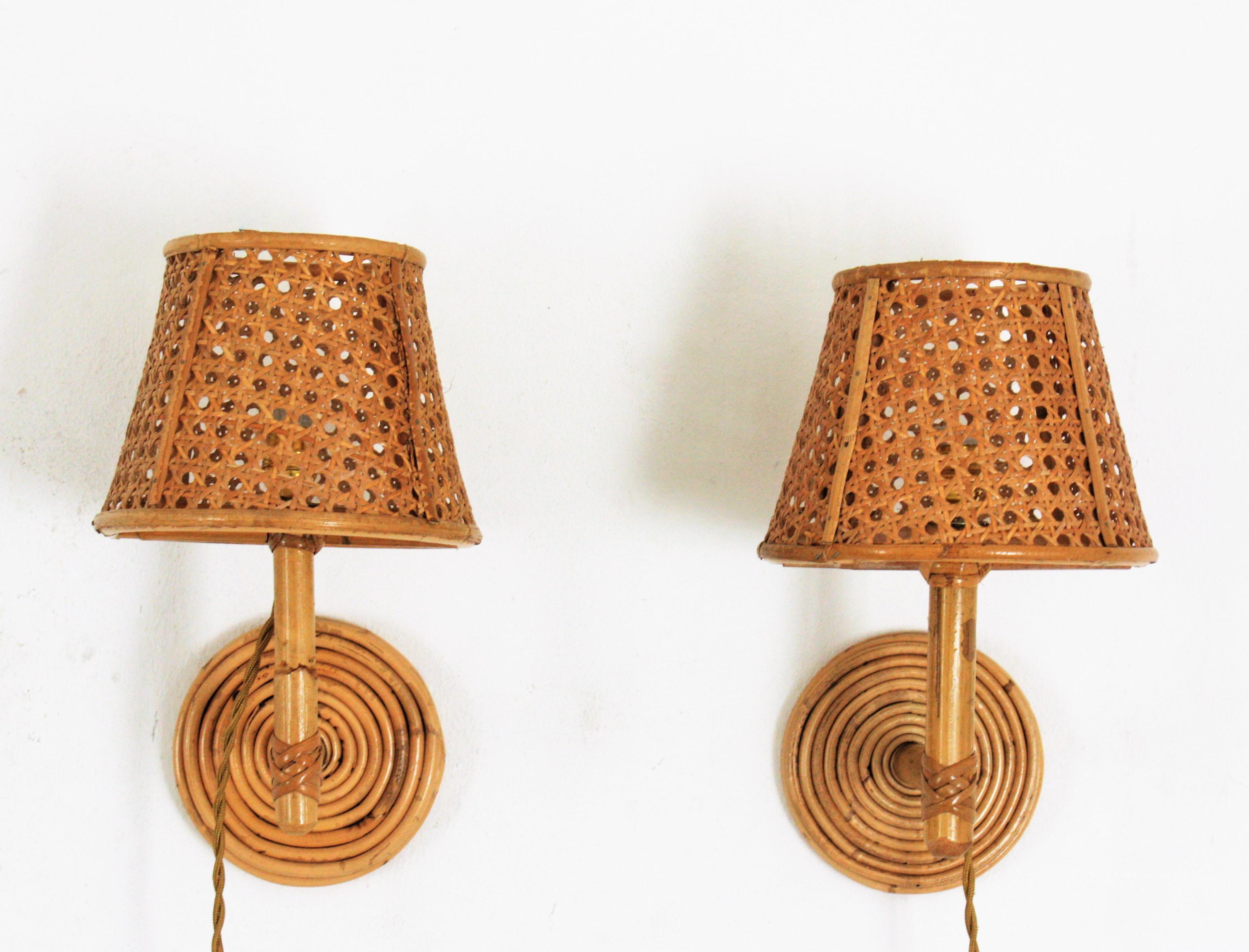 Eye-catching pair of Mid-Century Modern wicker and bamboo wall sconces with wicker weave shades: Italy, 1960s.
These wall lights feature round backplates covered with wicker holding bamboo arms with a wicker wire lampshades.
They will be the