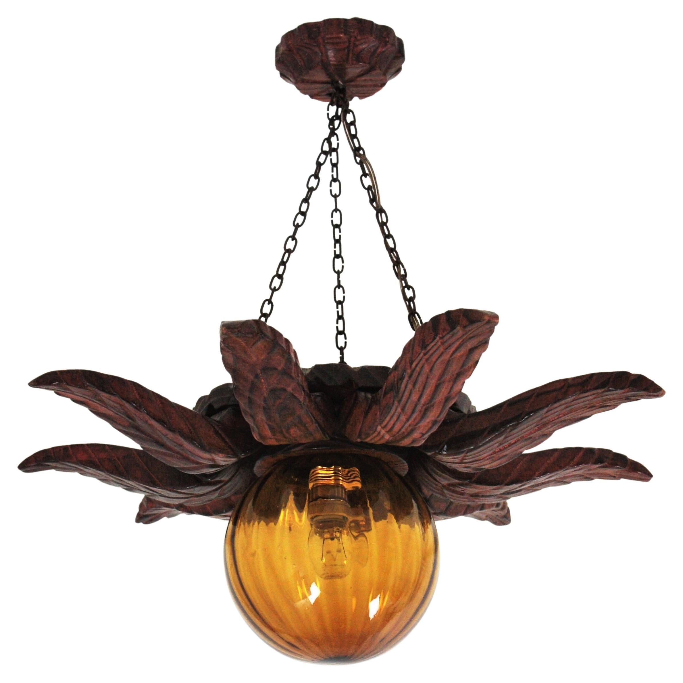 Spanish Colonial Sunburst Light Fixture in Carved Wood with Amber Glass Globe For Sale