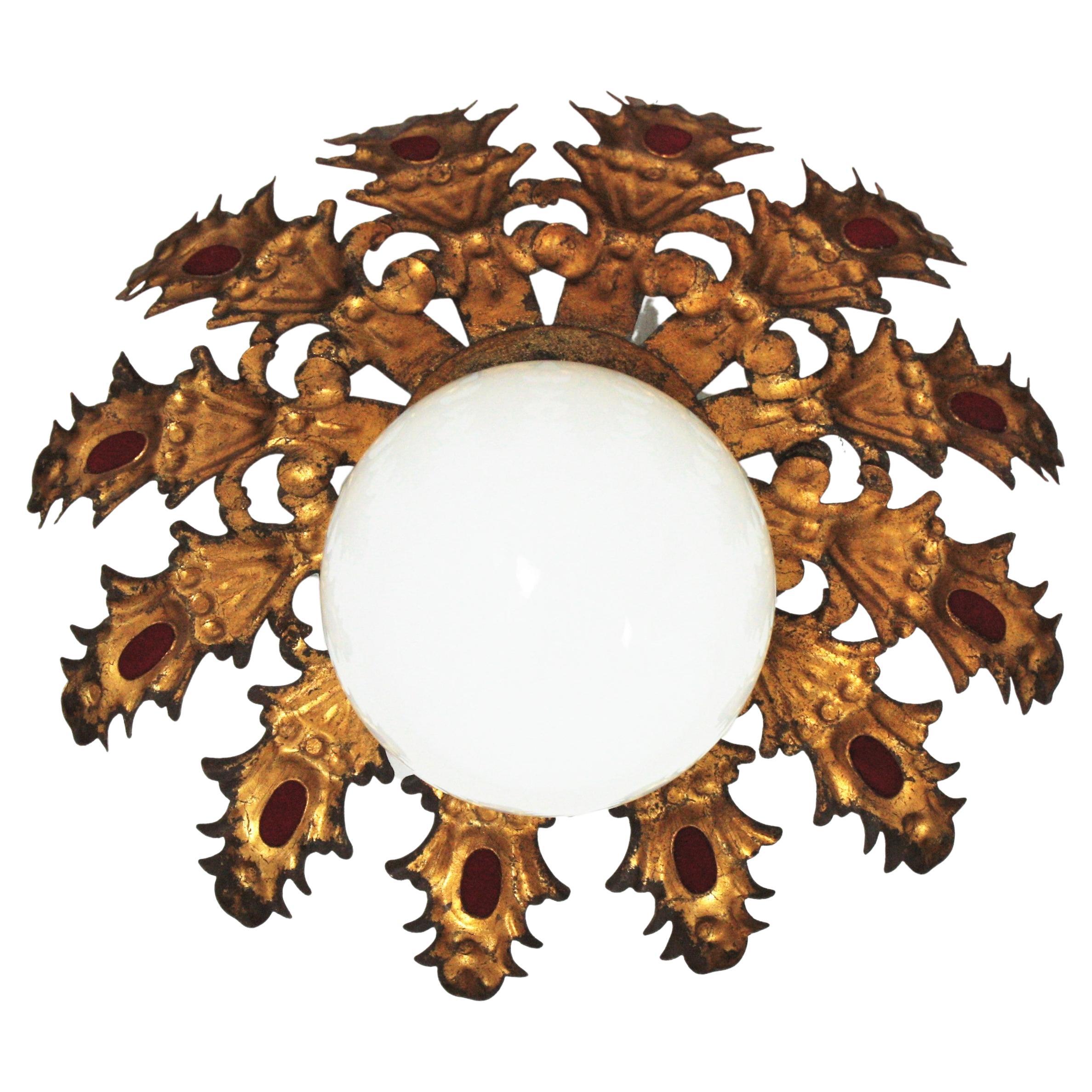 Eye catching sunburst light fixture with foliage design and milk glass globe shade, Spain, 1950s
This ceiling flush mount has a layer of leaves in gilt iron surrounding a central opaline glass globe shaped shade. It has some accents in red color on