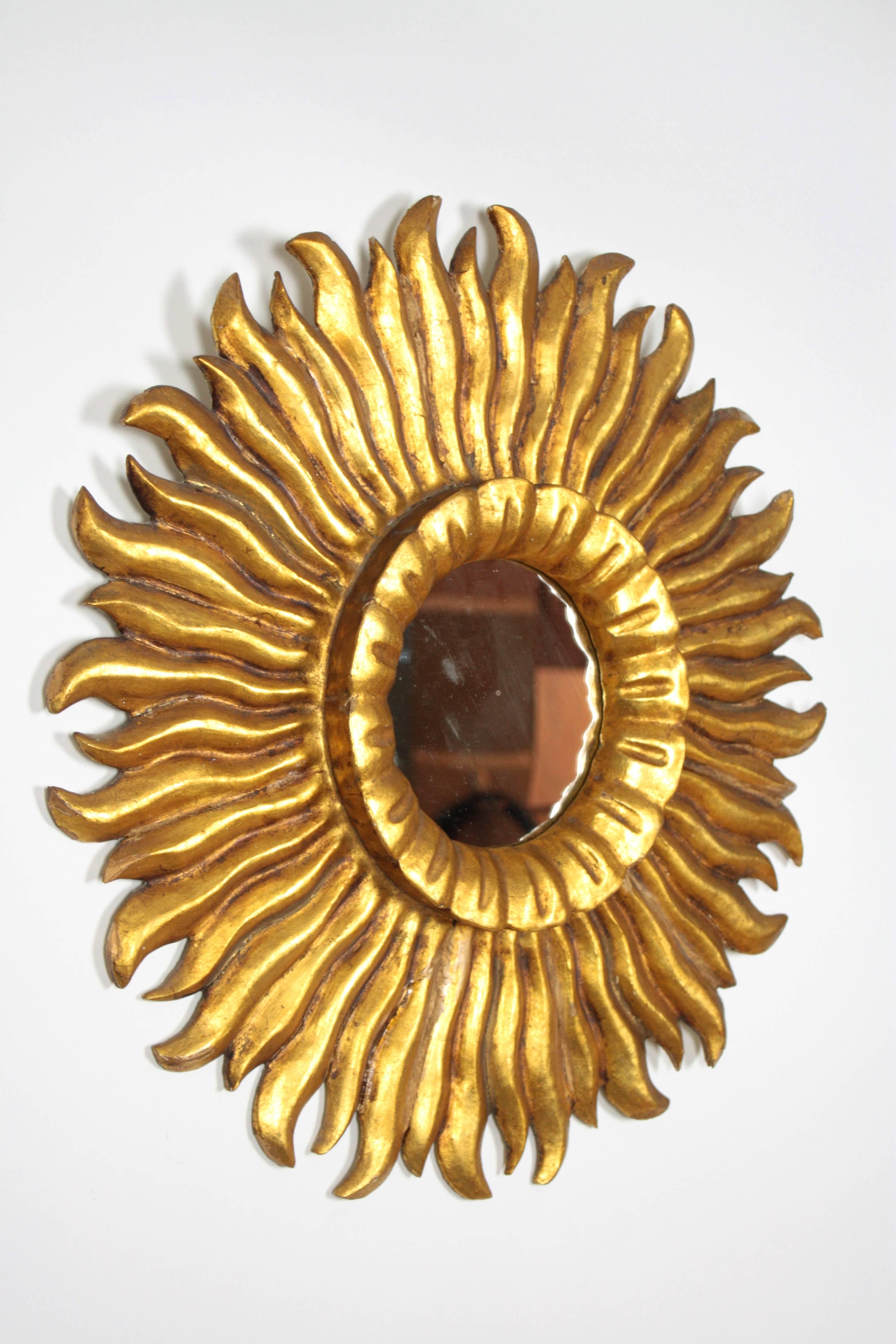 A very beautiful and finely carved sunburst mirror with gold leaf finish from the Hollywood Regency period. Carved wood covered with gesso and gold leaf. Made in Spain, circa 1930s.
 