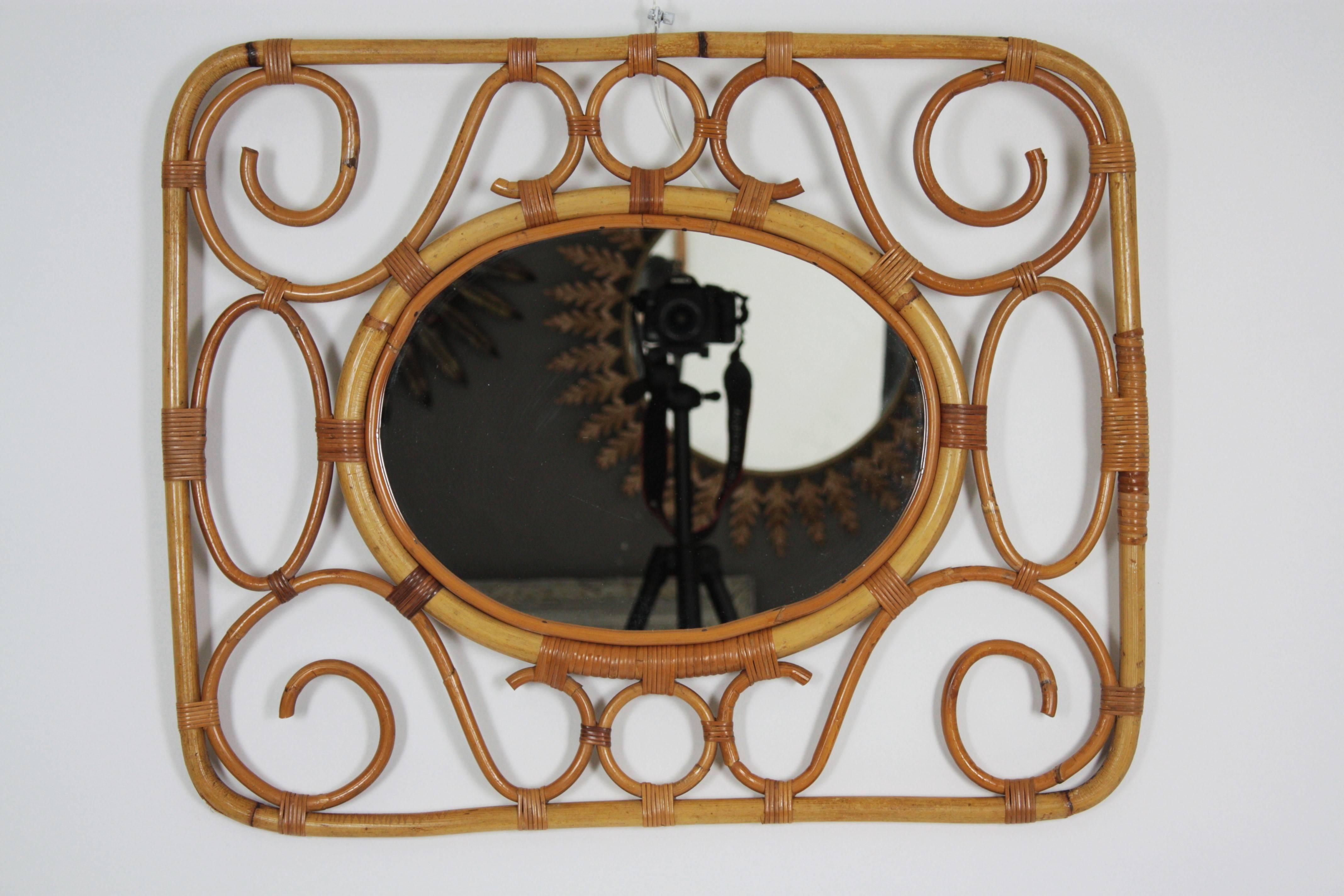 Lovely handcrafted bamboo and rattan frame surrounding an oval mirror,
Spain, 1960s.

Beautiful to place alone or creating a wall decoration with other bamboo or rattan mirrors. It can be hanged in two positions.
Avaliable a huge collection of