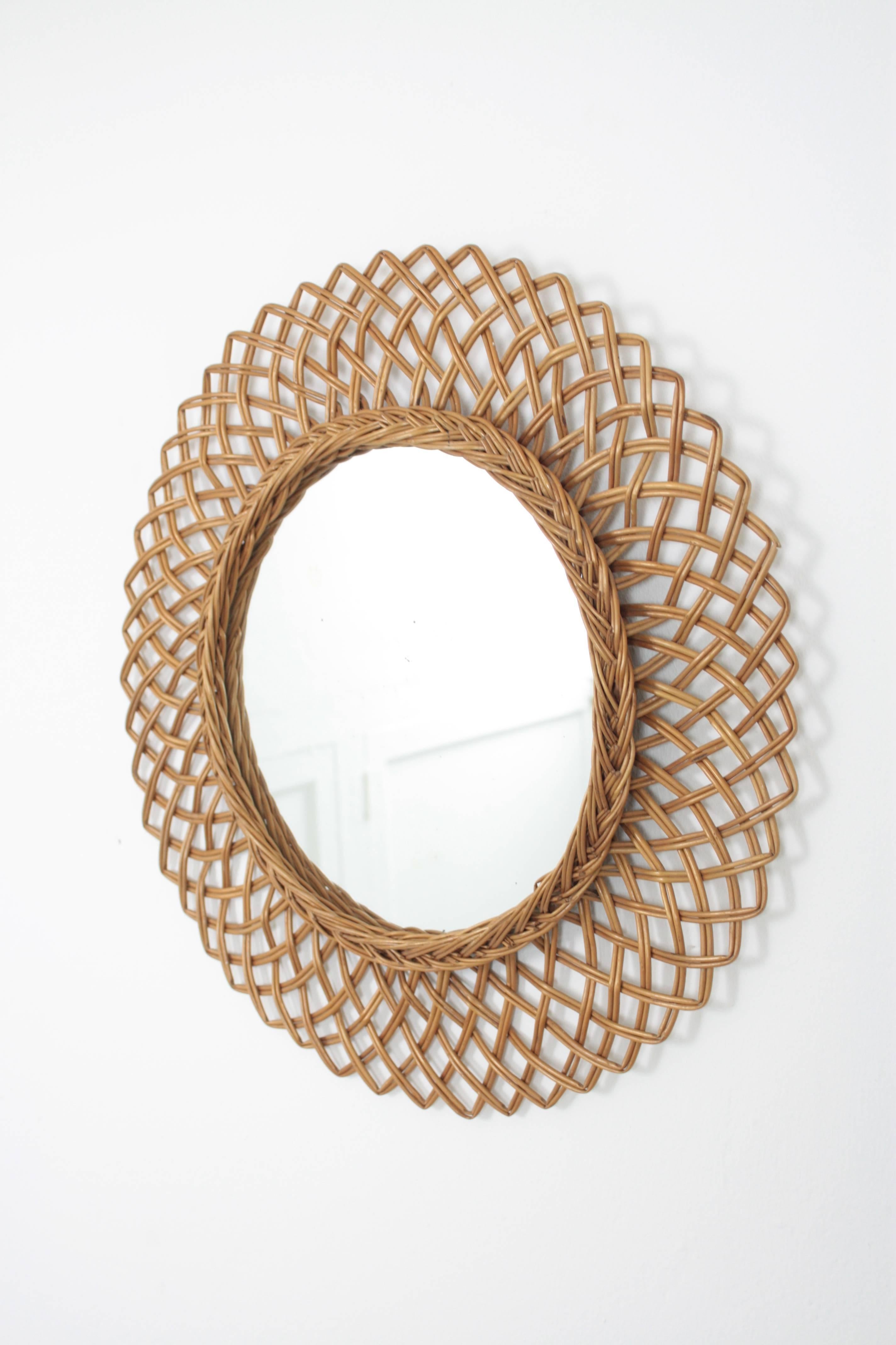 Lovely handcrafted rattan mirror with highly decorative hand-braided frame.
Beautiful to create a wall decoration with other mirrors in this manner or to place it alone. 
Amazing Mediterranean style taste.
Spain, 1960s.
Measures: 50 cm diameter //