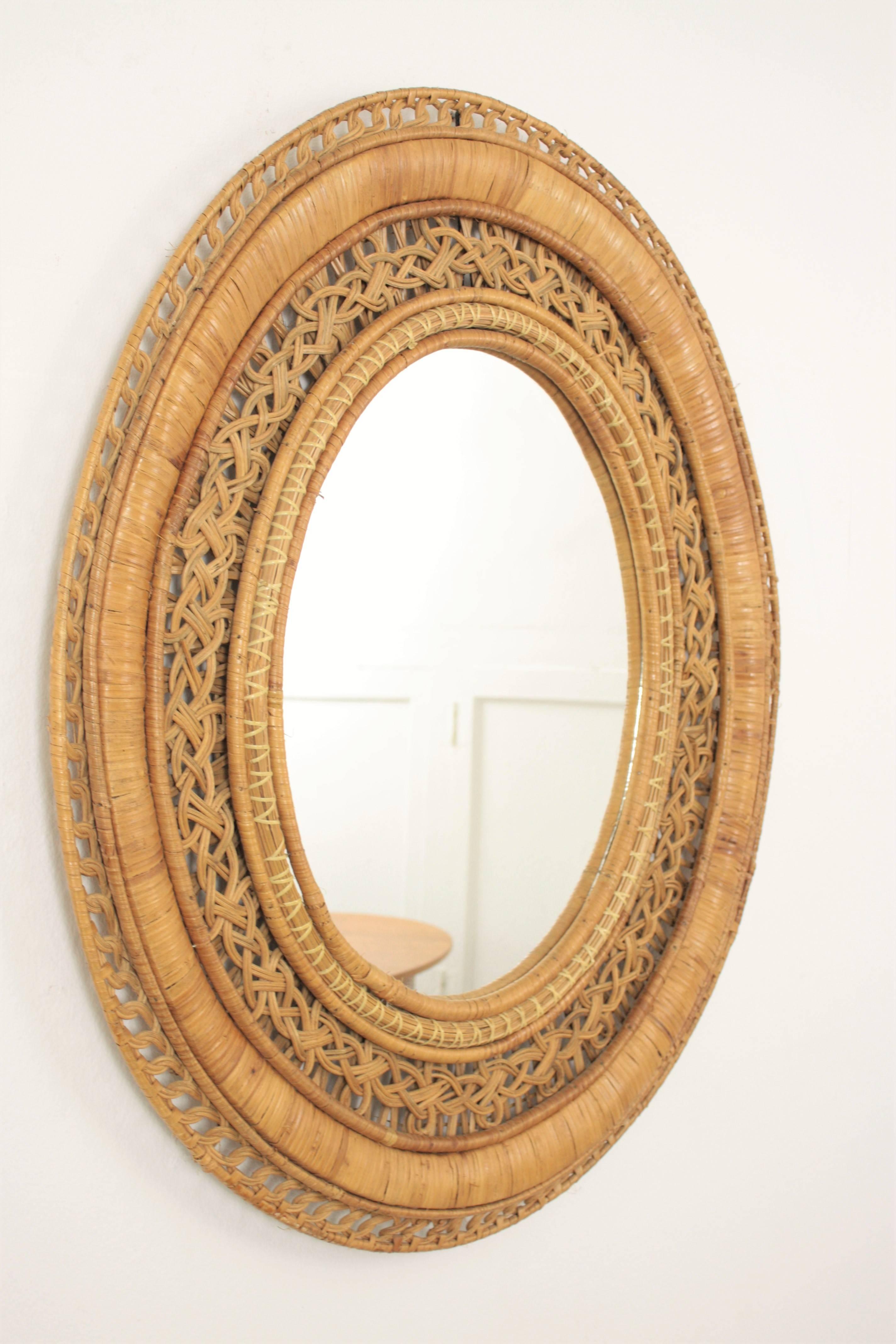 French handcrafted mirror with a woven wicker and rattan frame full of decorative filigree details. Hand made in the style of the Emmanuelle peacock chair, France, 1960s.

Lovely to place it alone or creating a wall decoration with other mirrrors in
