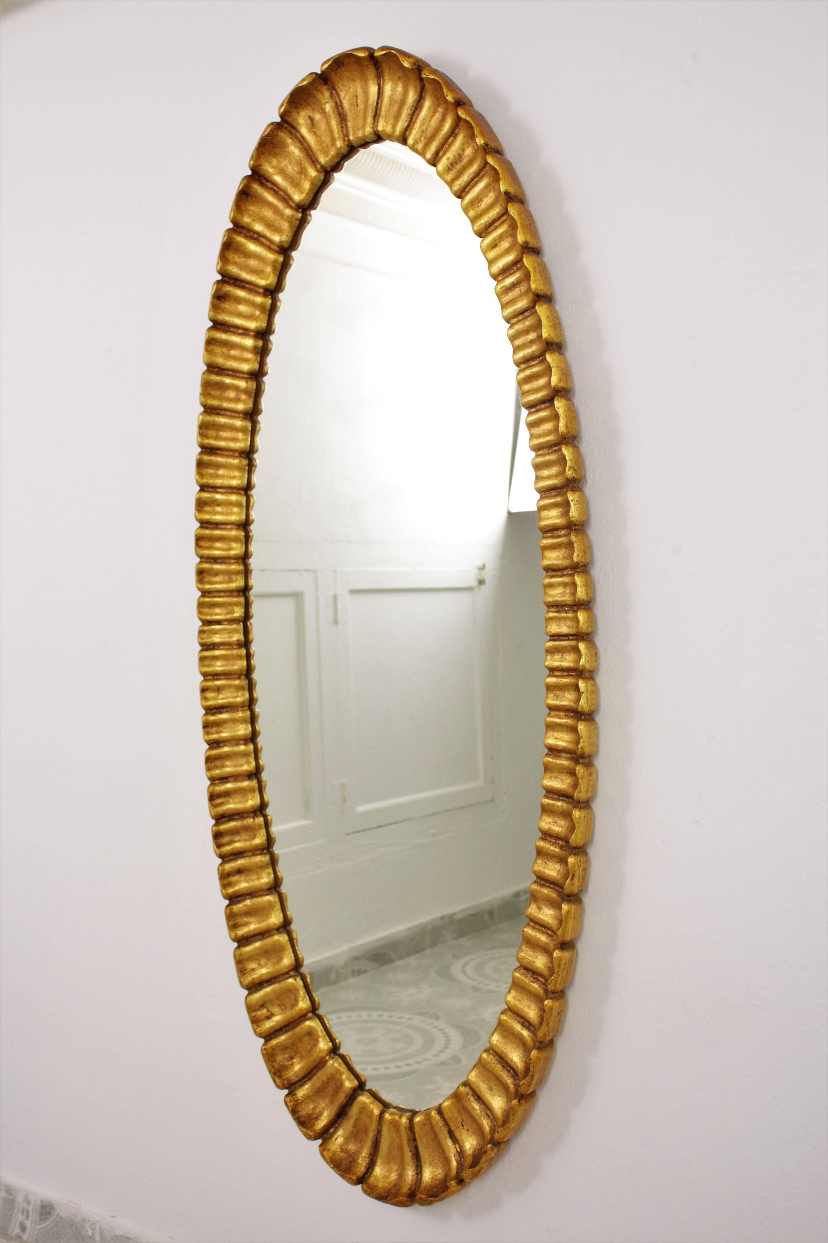 Sculptural and finely carved Hollywood Regency style scalloped giltwood mirror with gold-leaf finish. Amazing patina.
Designed and manufactured by Francisco Hurtado.
Original label of the workshop at the back.

Spain, 1950s.

