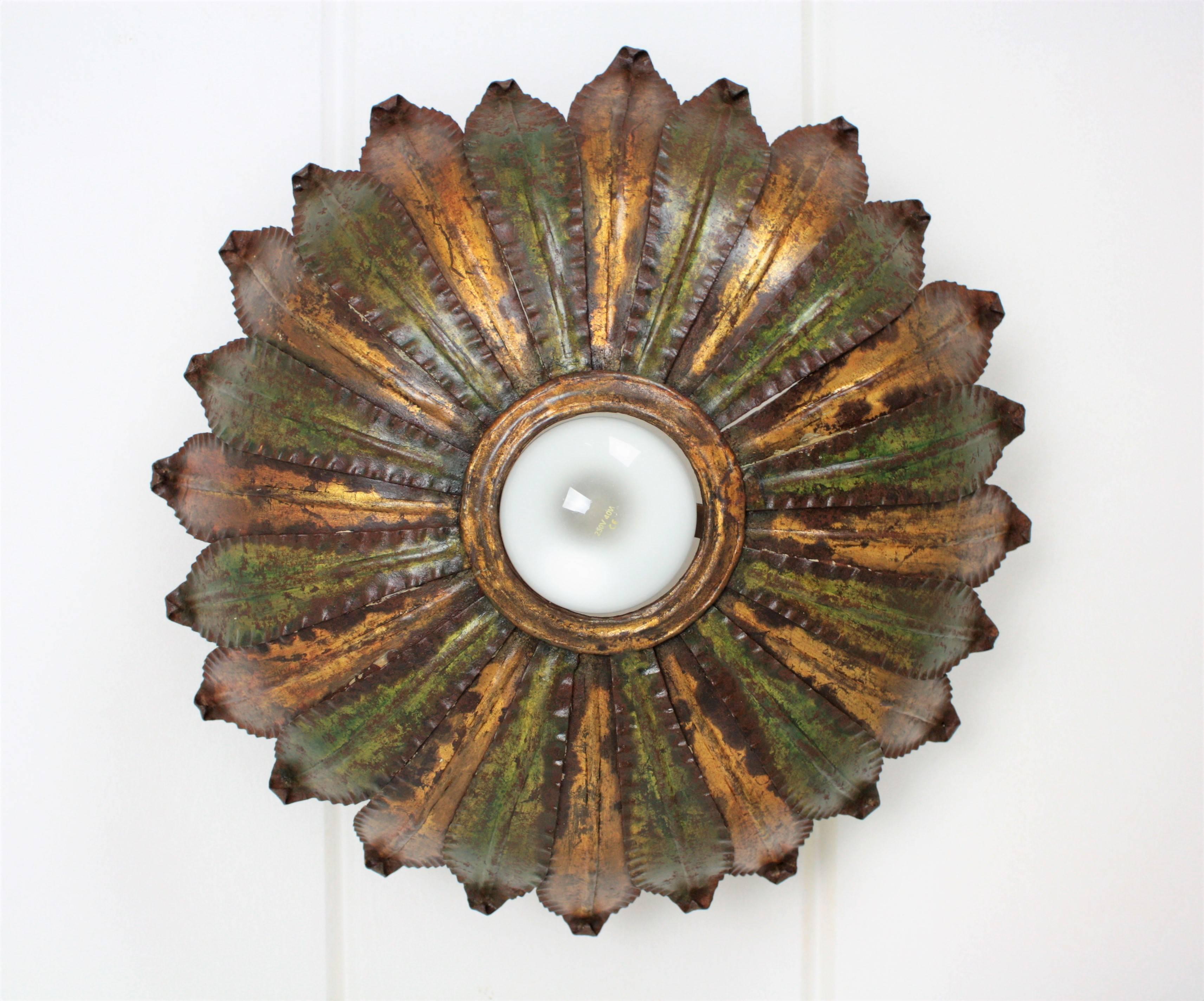 Amazing hand-hammered iron sunburst light fixture with a highly decorative original patina in gold leaf and green color with rusty accents. The two tones finish and its shape make this ceiling sconce different and unique. It could work also as wall