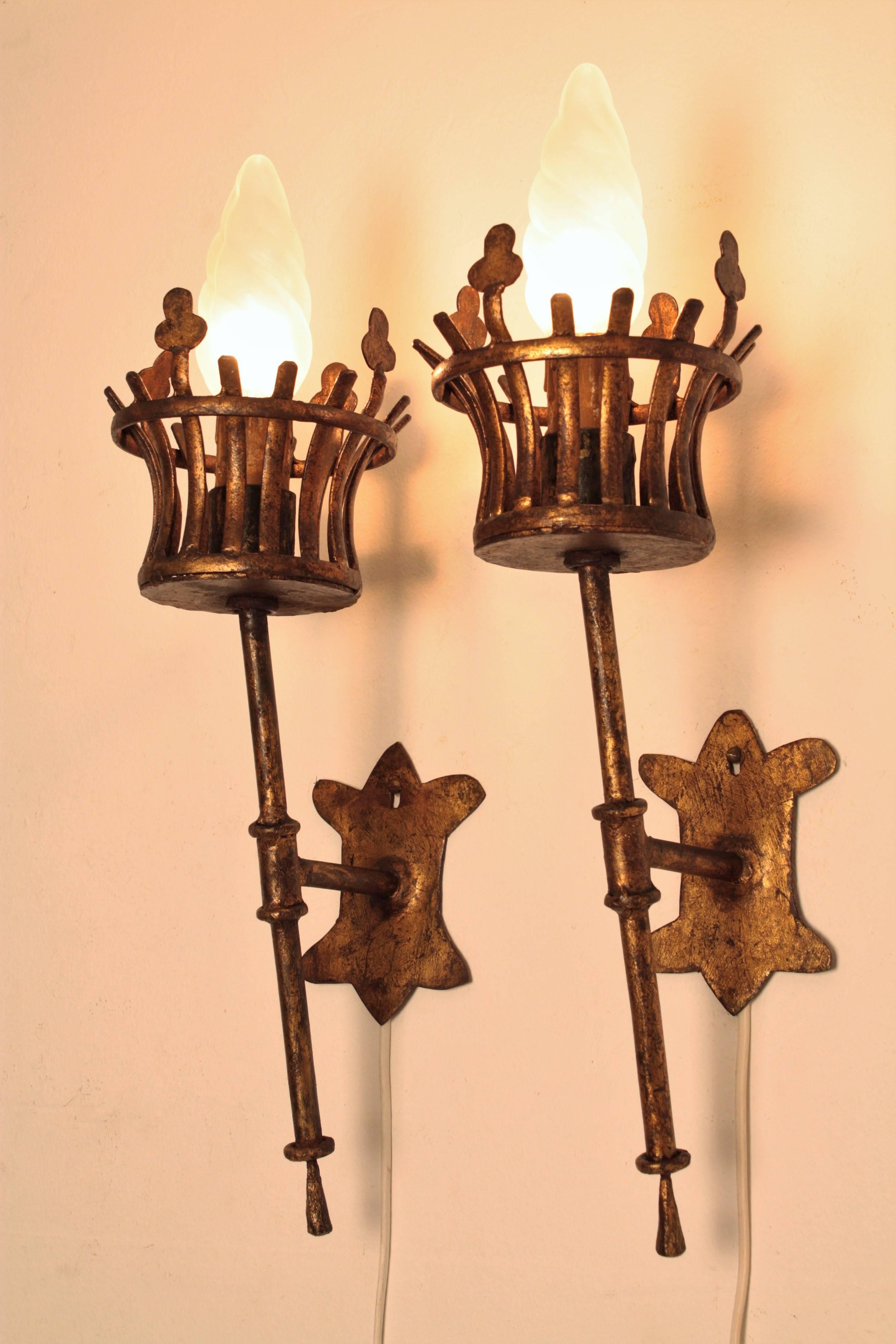 A pair of hand-hammered iron torch wall sconces with gold leaf finish and gorgeous original patina in Medieval style.
These pieces were handcrafted and have highly decorative shapes. They have been new rewired.
France, 1930s-1940s.

Available