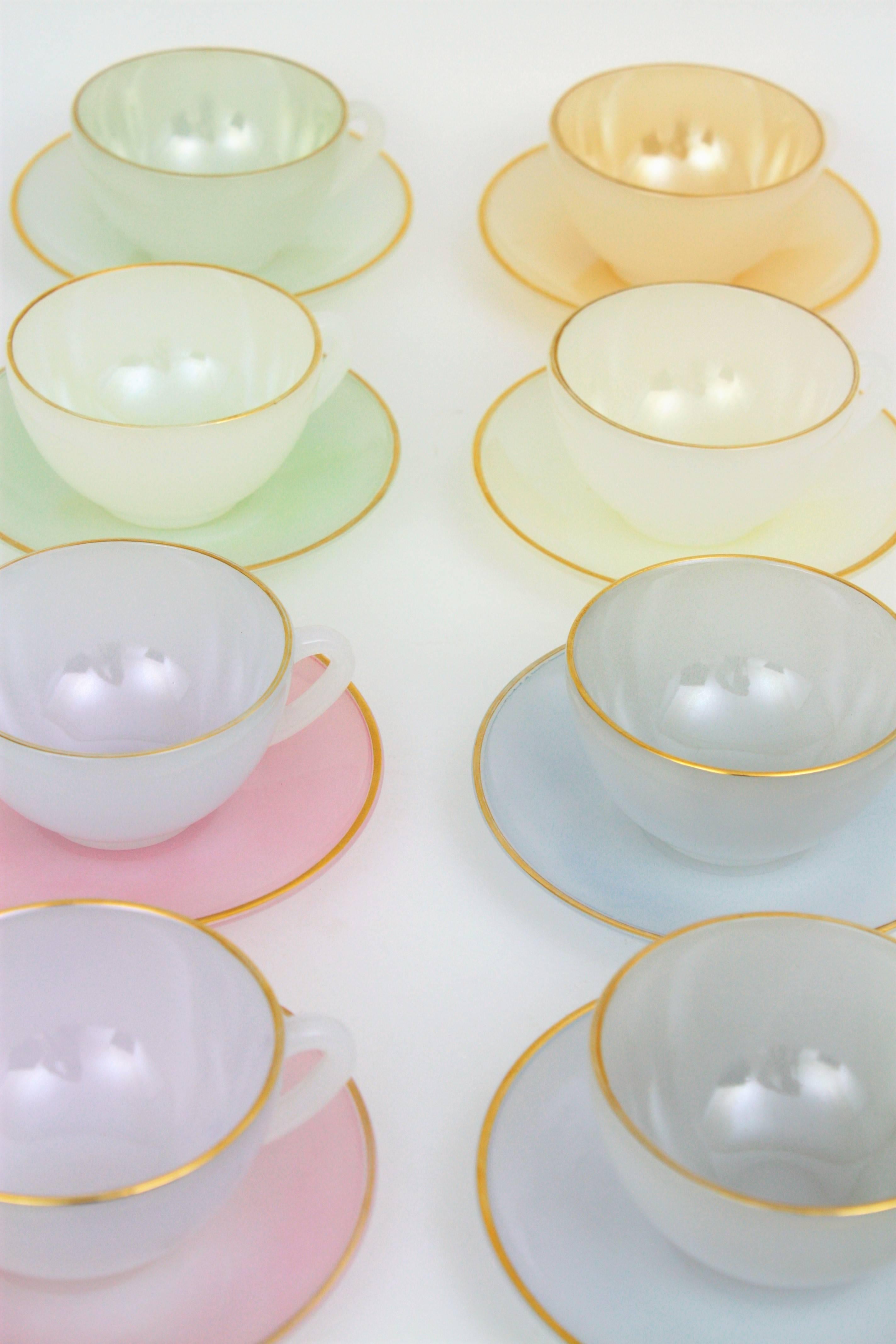 A highly decorative set of eight Harlequin opalescent pastel colors glass tea or coffee cups and dishes. Blue, green, peach and pink colors with a golden ribbon covering the edges of the plates and the cups. 
Manufactured by Arcopal, France,