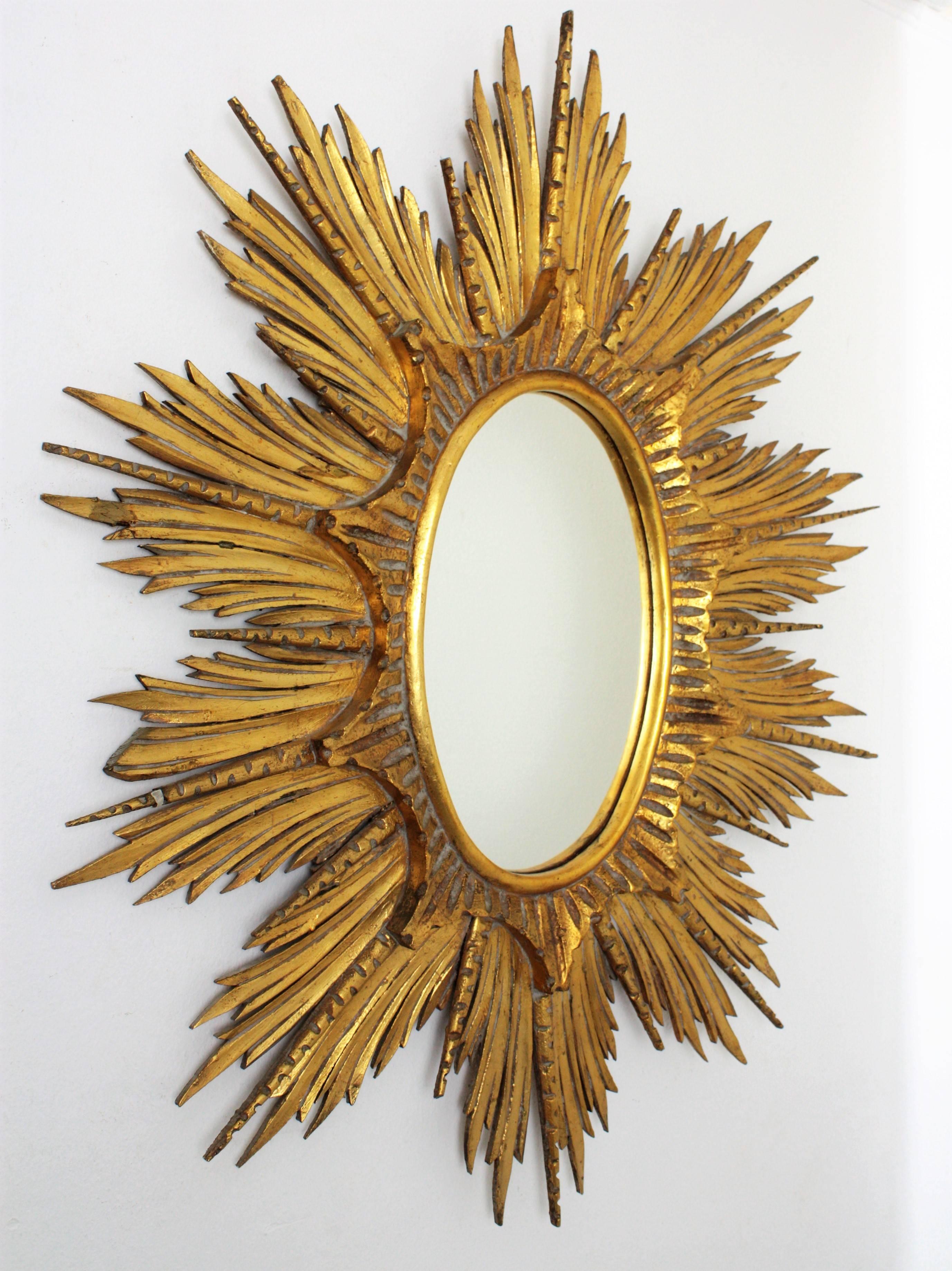 A gorgeous oval shaped gold leaf giltwood sunburst mirror. The frame is finely carved and it has a layer of beams in two sizes and different shapes and a layer with starburst shape surrounding the glass.
This piece is in excellent vintage condition