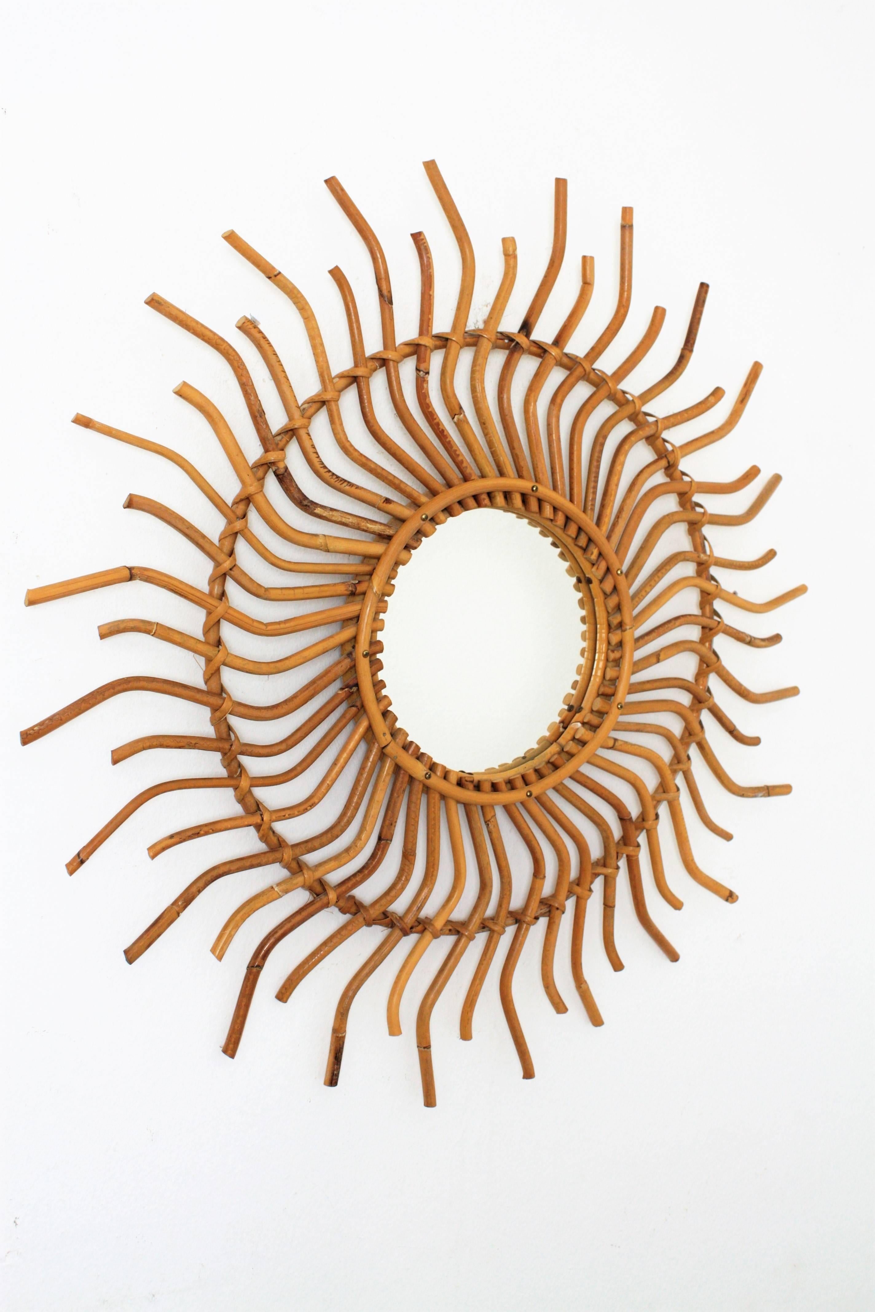 Spectacular midcentury modernist bamboo and rattan sunburst mirror with curly beams. Its pinwheel shape make this mirror specially beautiful.
Amazing to place it alone or in a wall decoration with other mirrors in natural fiber, 
Spain,