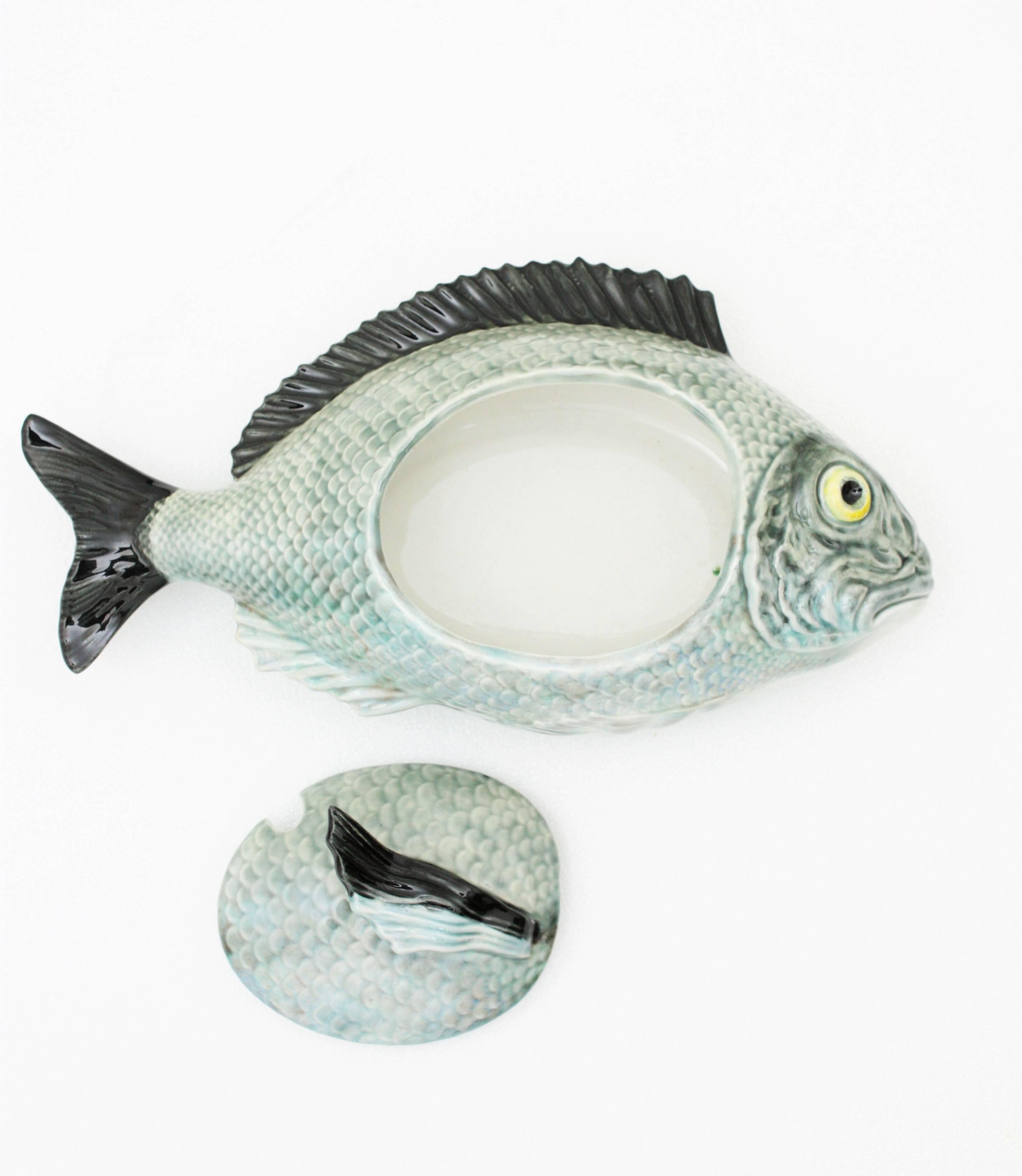 A magnificent big size hyper realistic glazed ceramic fish tureen in shades of blue, green and grey with black accents manufactured by Rafael Bordalo Pinheiro. Portugal, 1950s.
A beautiful example of the traditional Portuguese Majolica ceramic. This