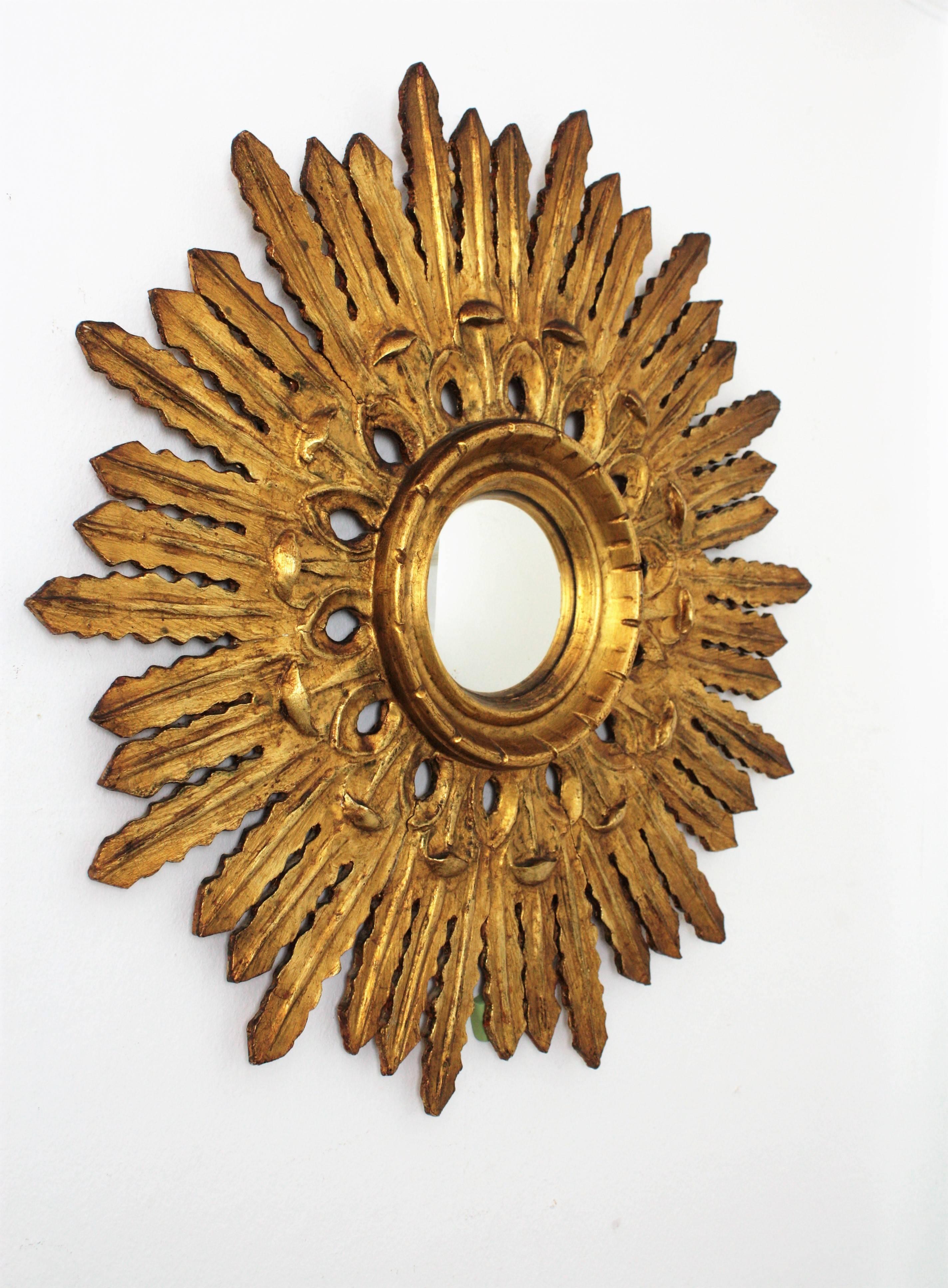 An exquisite finely carved Baroque style sunburst mirror with a carved filigrana decoration surrounding the convex glass. The sunburst shape and the lovely floral corolla surrounding the glass make this piece highly decorative. Wood covered with