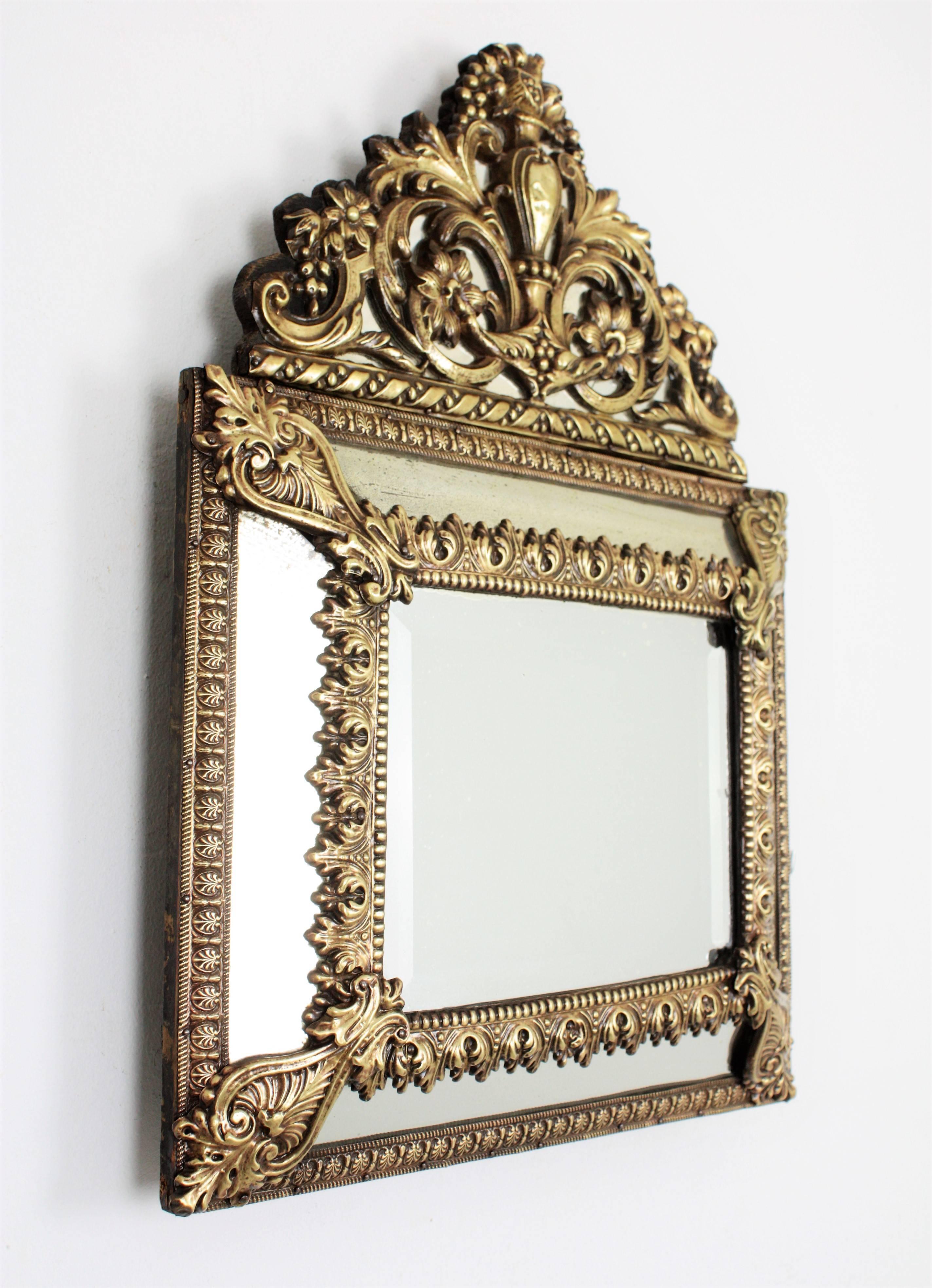 An elegant Napoleon III period mirror made with central beveled glass and four rectangular glasses joined between them by decorative brass repousse floral patterns, an elegant filigree repousse brass crest and sculptural Acanthus leaves adorning the