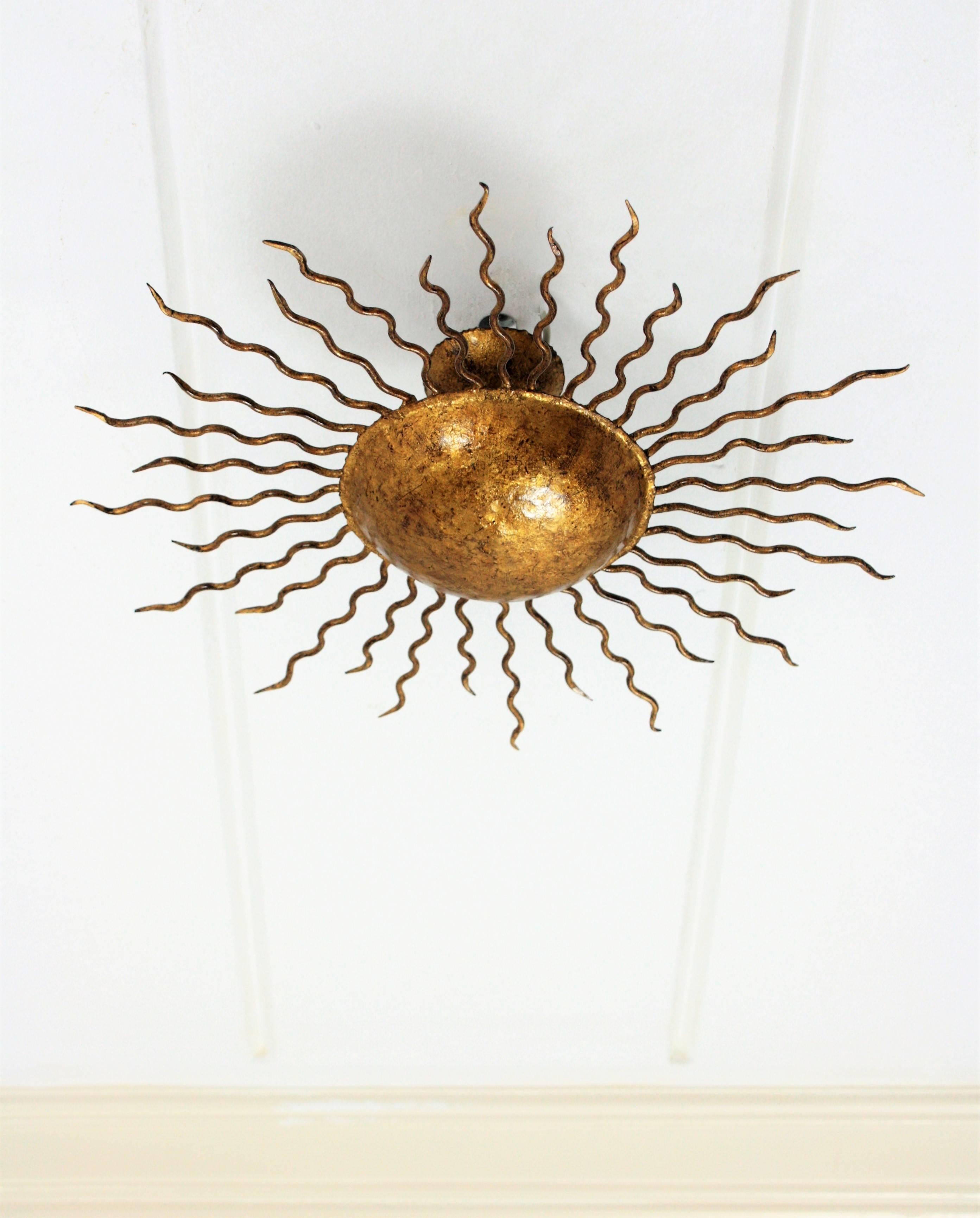 A hand-hammered sunburst gilt iron light fixture with curvy beams in different sizes. It can be used as ceiling light fixture, wall sconce or wall decoration. Spain, 1960s.
Measures: 42 cm diameter x 16 cm H.

Avaliable a huge collection of sunburst