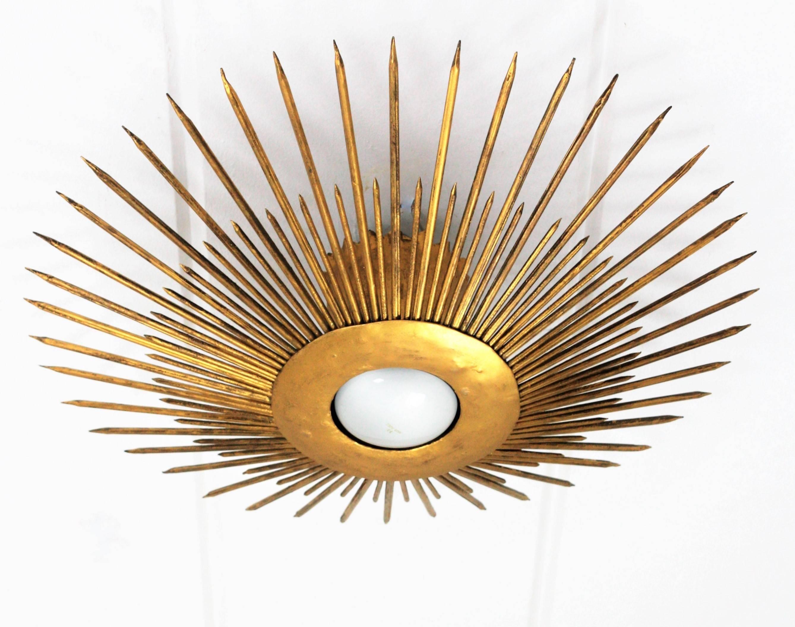 A hand-hammered gilt sunburst ceiling light fixture with gold leaf finish and Art Deco accents in transition to Brutalist style. France, 1930s-1940s.
A highly decorative piece with frontal Light. It has iron nails in two sizes as sun beams