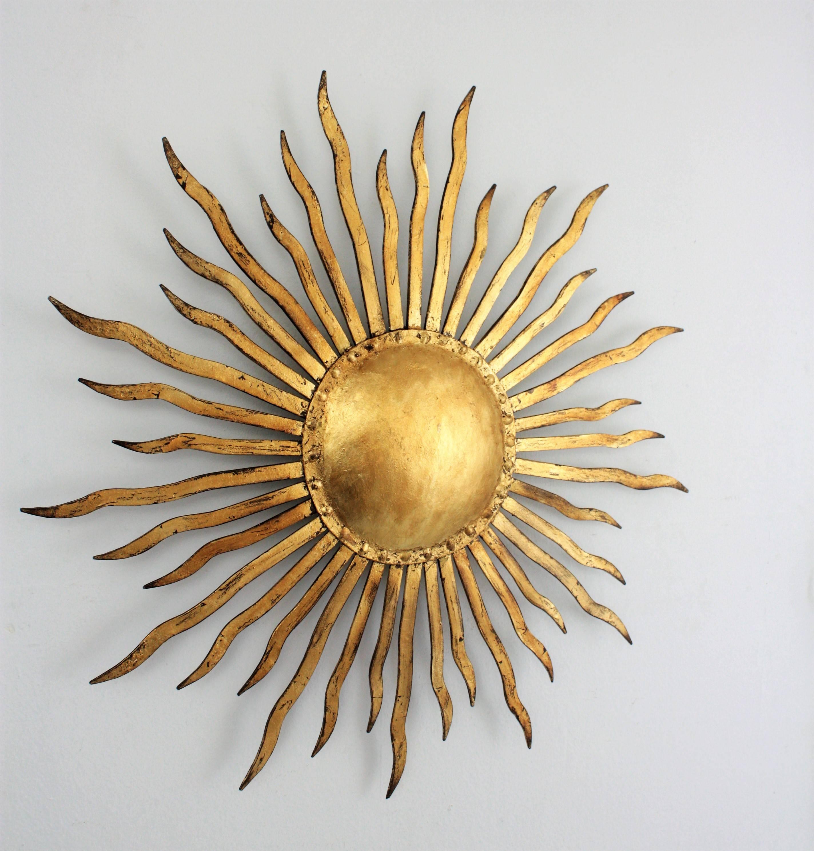 A beautiful sunburst wall sconce or wall sculpture with gold leaf finish made in wrought iron. It has beautiful details of nails surrounding the central sphere, Spain, 1950s
Lovely to place it alone but also gorgeous mixed with other wall