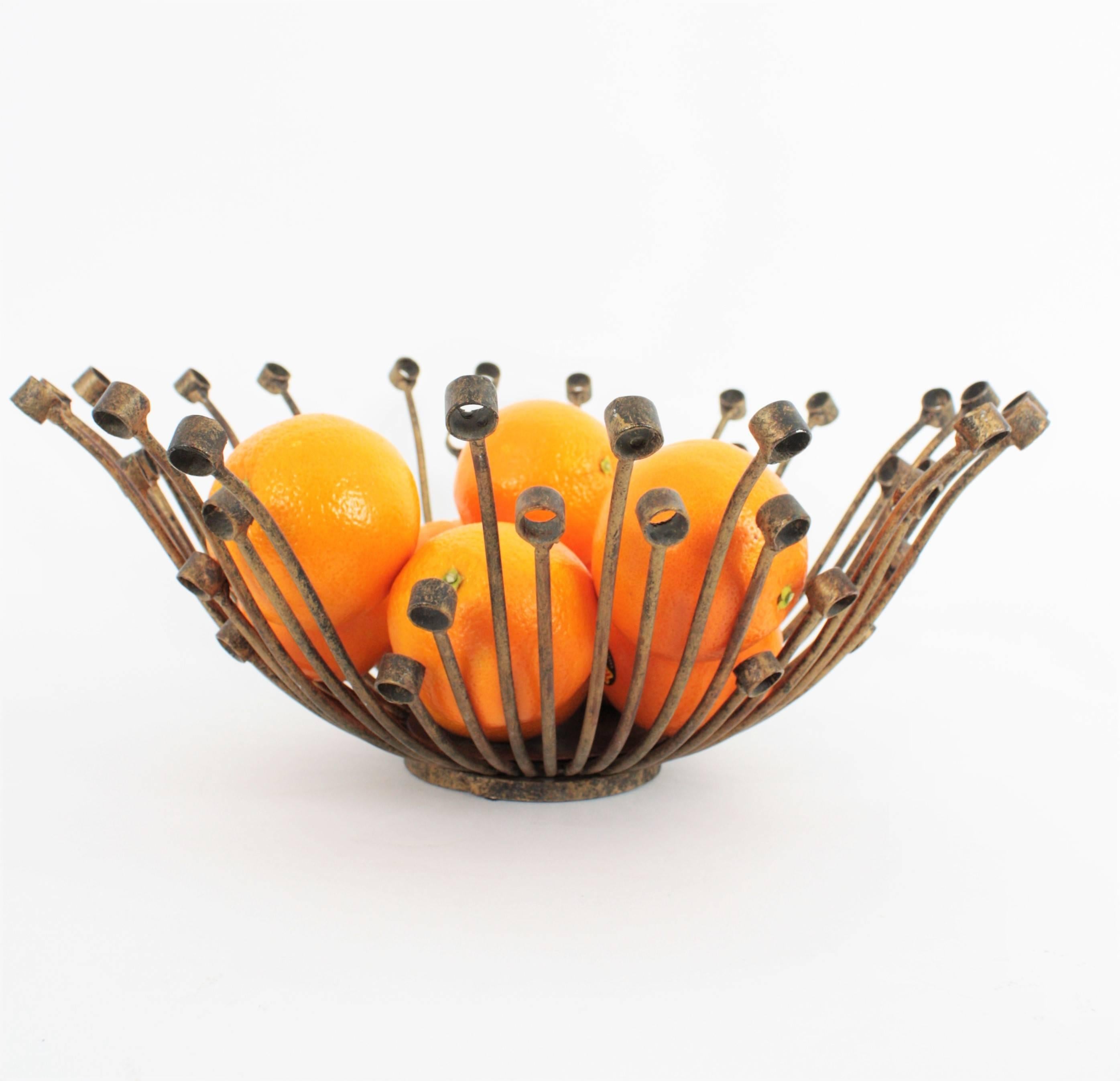 Unusual hand-hammered iron centerpiece or fruit bowl with gold leaf accents with sunburst shape. This hand crafted piece is made with iron tubes placed as sun beams and finished by iron rings. Its design is sculptural and highly decorative. 
Spain,