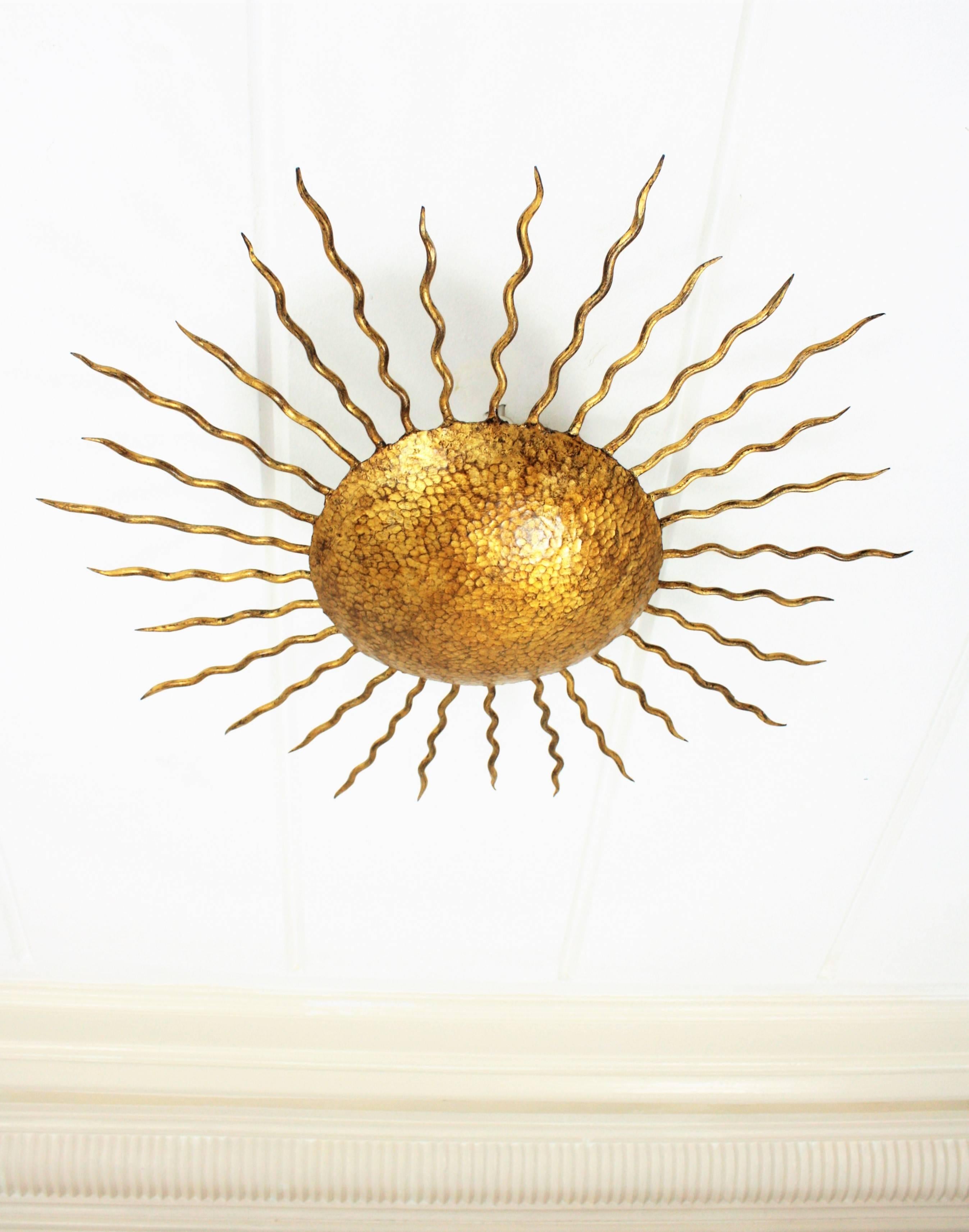 Gold leaf gilt iron sunburst light fixture from the Brutalist period. Richly decorated in the center part with hand-hammered marks. Beautiful to place as ceiling light fixture but also as a wall sconce, Spain, 1950s.
Avaliable more pieces in this