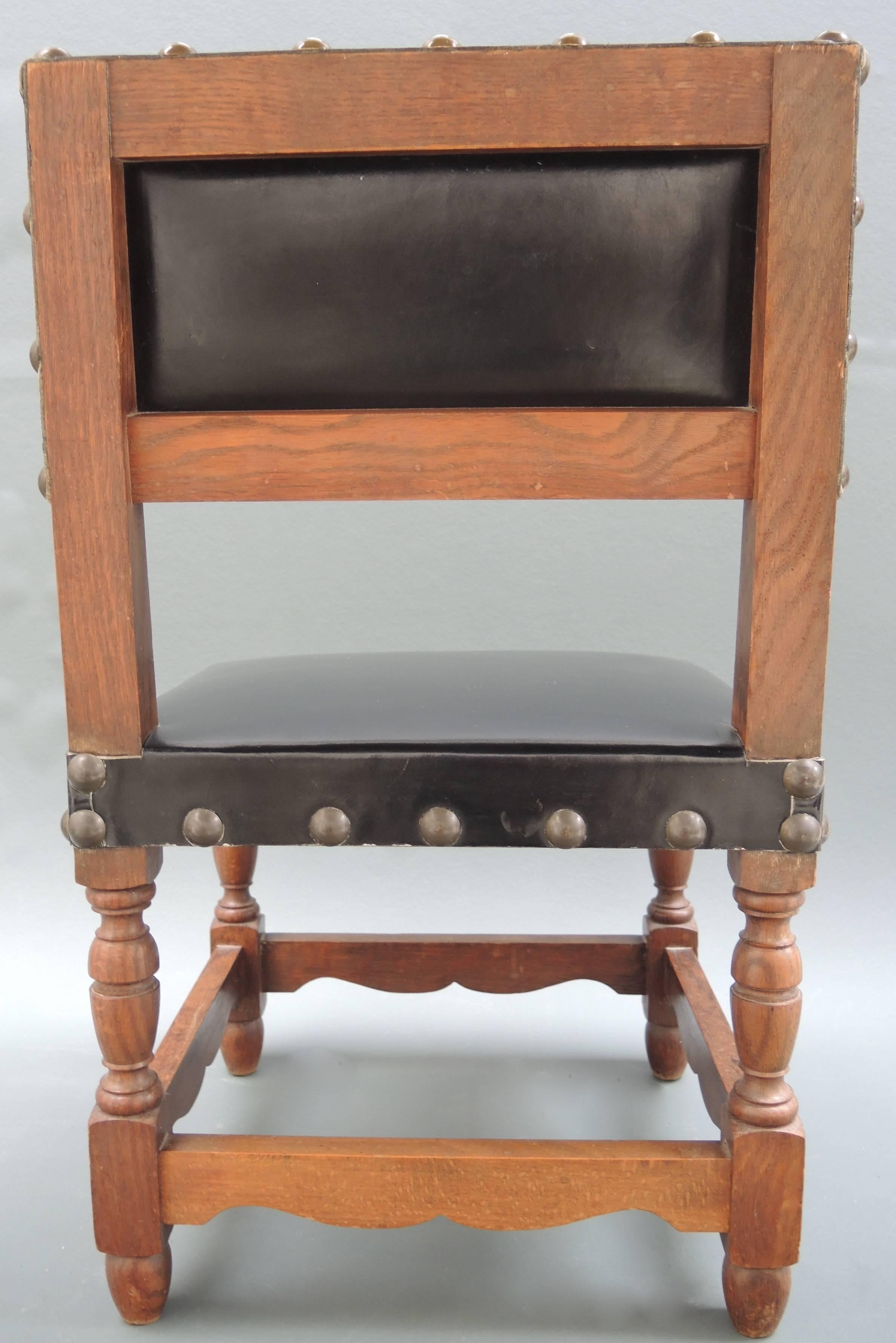 This elegant childs chair is made from solid oak and bears the original black leather upholstery and brass nailhead trim . 
Would be great used as an original side table stacked with books.