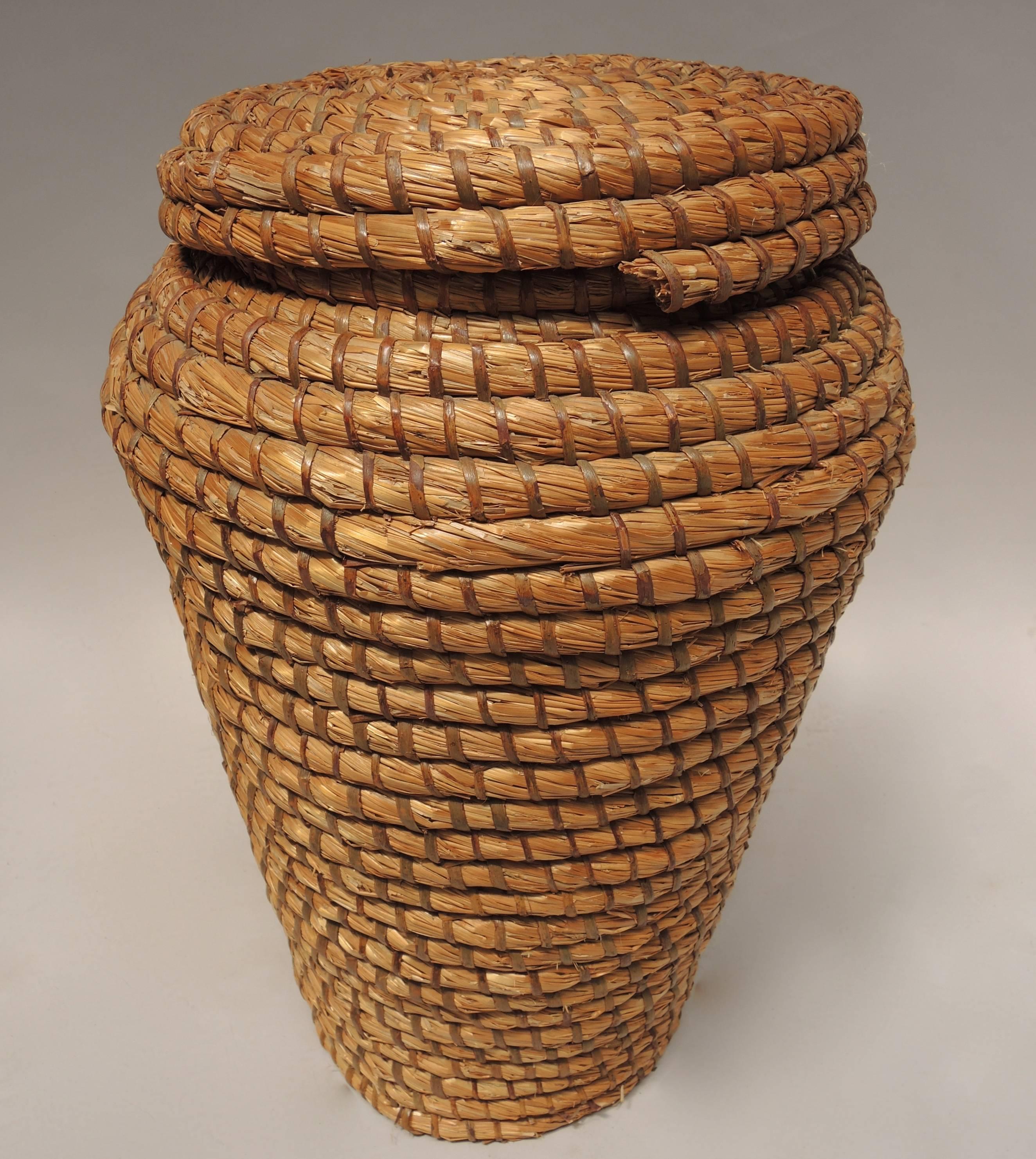 This lidded Belgian farm basket is hand constructed using straw and split oak.
The tightly coiled construction was used to make a durable basket that could be used for multiple tasks on the farm.