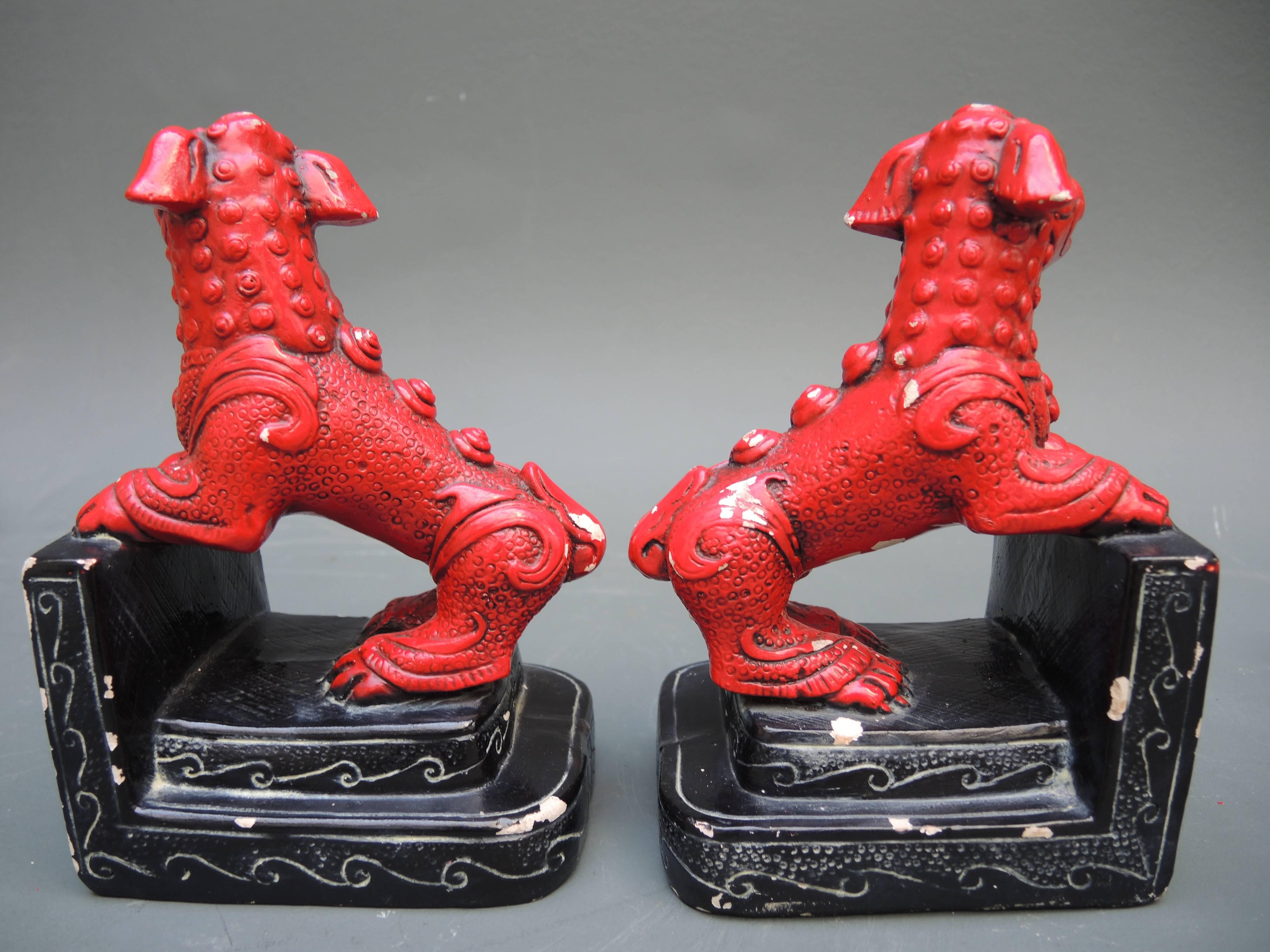 This pair of foo dog bookend statues epitomise the chic Hollywood Regency style of the 1940s. They are cast of chalkware and retain the original lacquer paint in red and black. There are some chips to the paint as seen in the photos, but otherwise