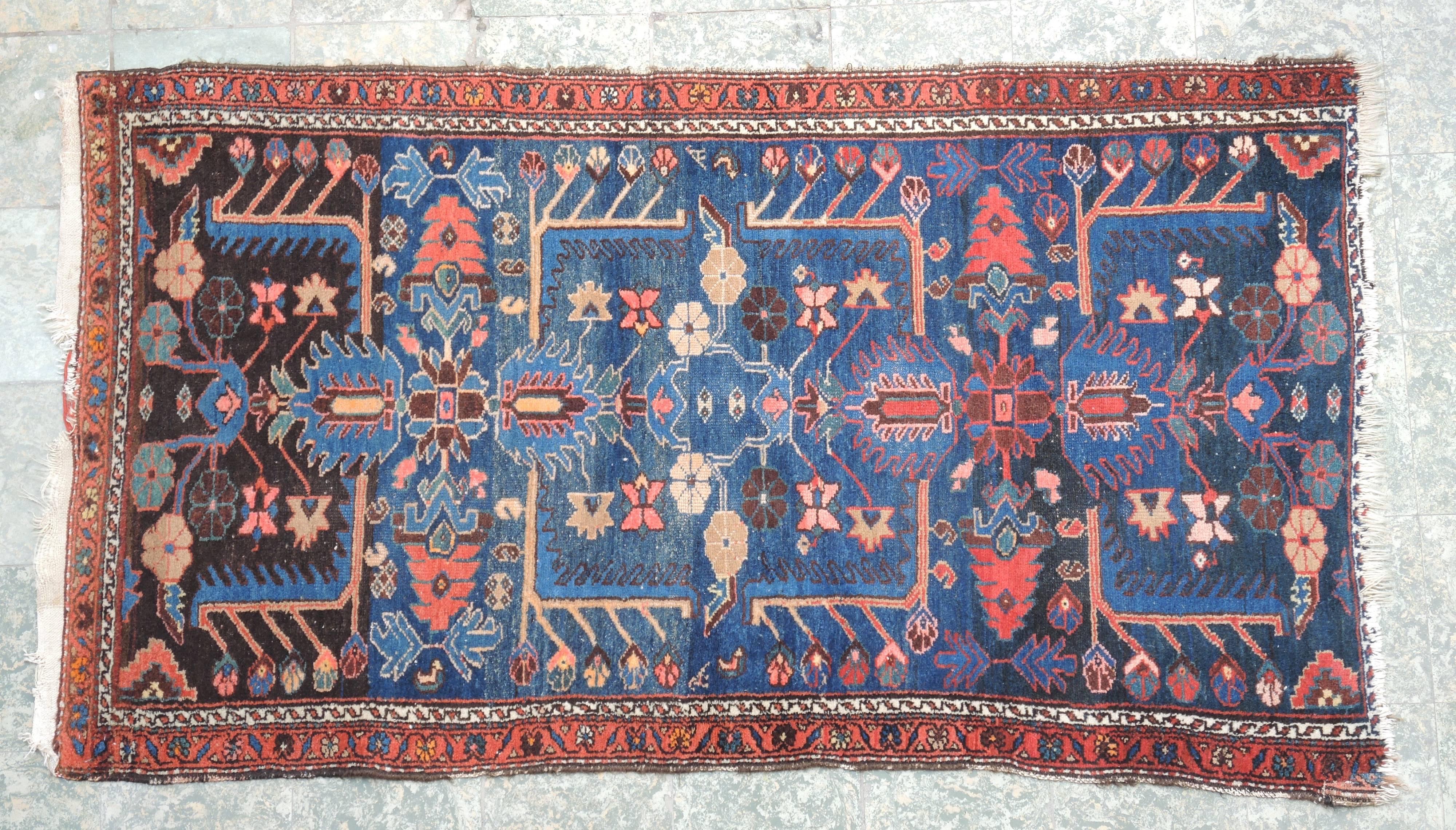 Graphic design and rich blue and wine colors make this Persian carpet a versatile piece to use in a modern or traditional setting.