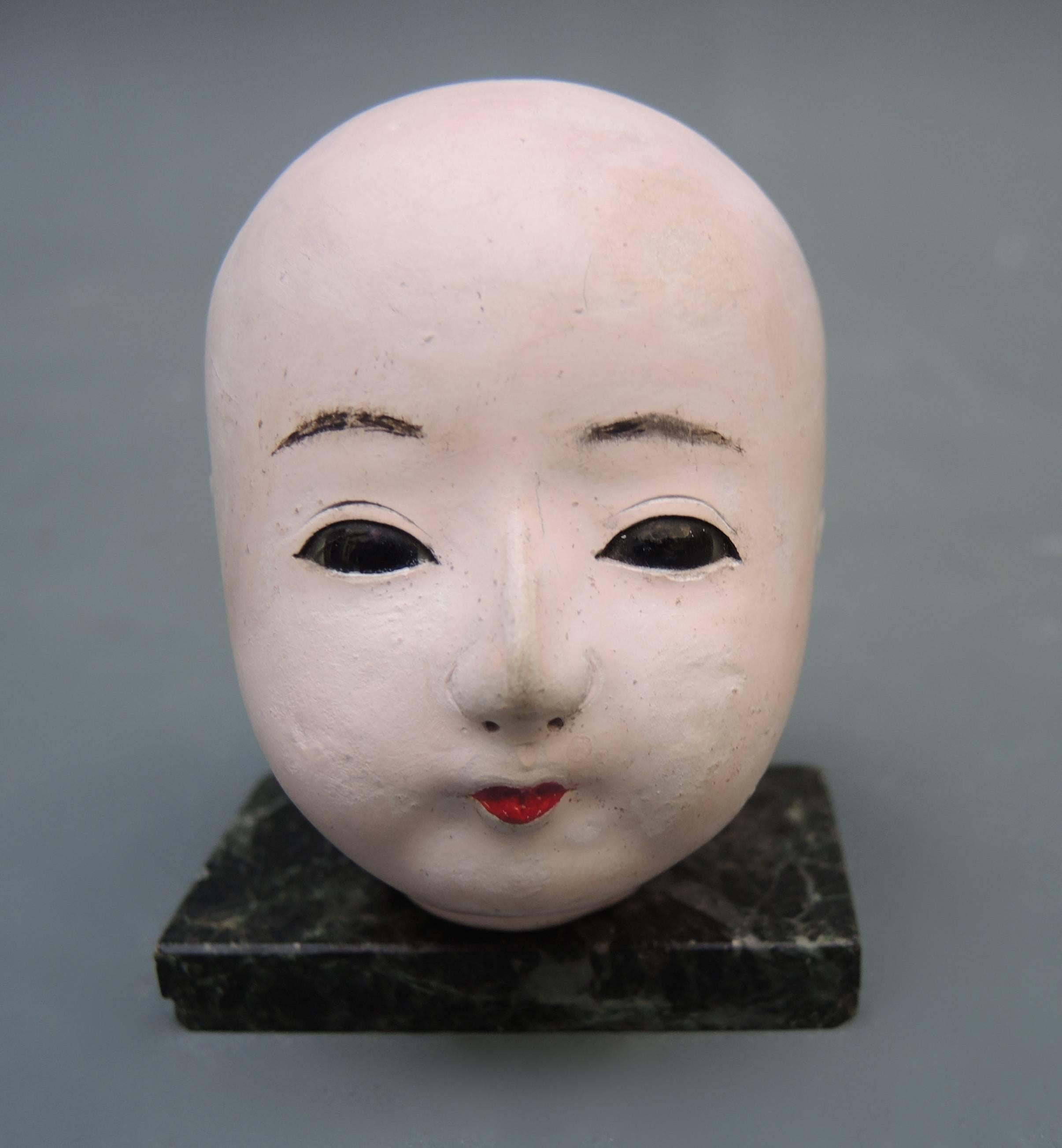 A very elegant Japanese papier mâché and oyster paste Ichimatsu doll head. The eyes are black reverse painted glass and the head is hand-sculpted in papier mâché, coated in a paste made from crushed oyster shells and then delicately hand-painted.
