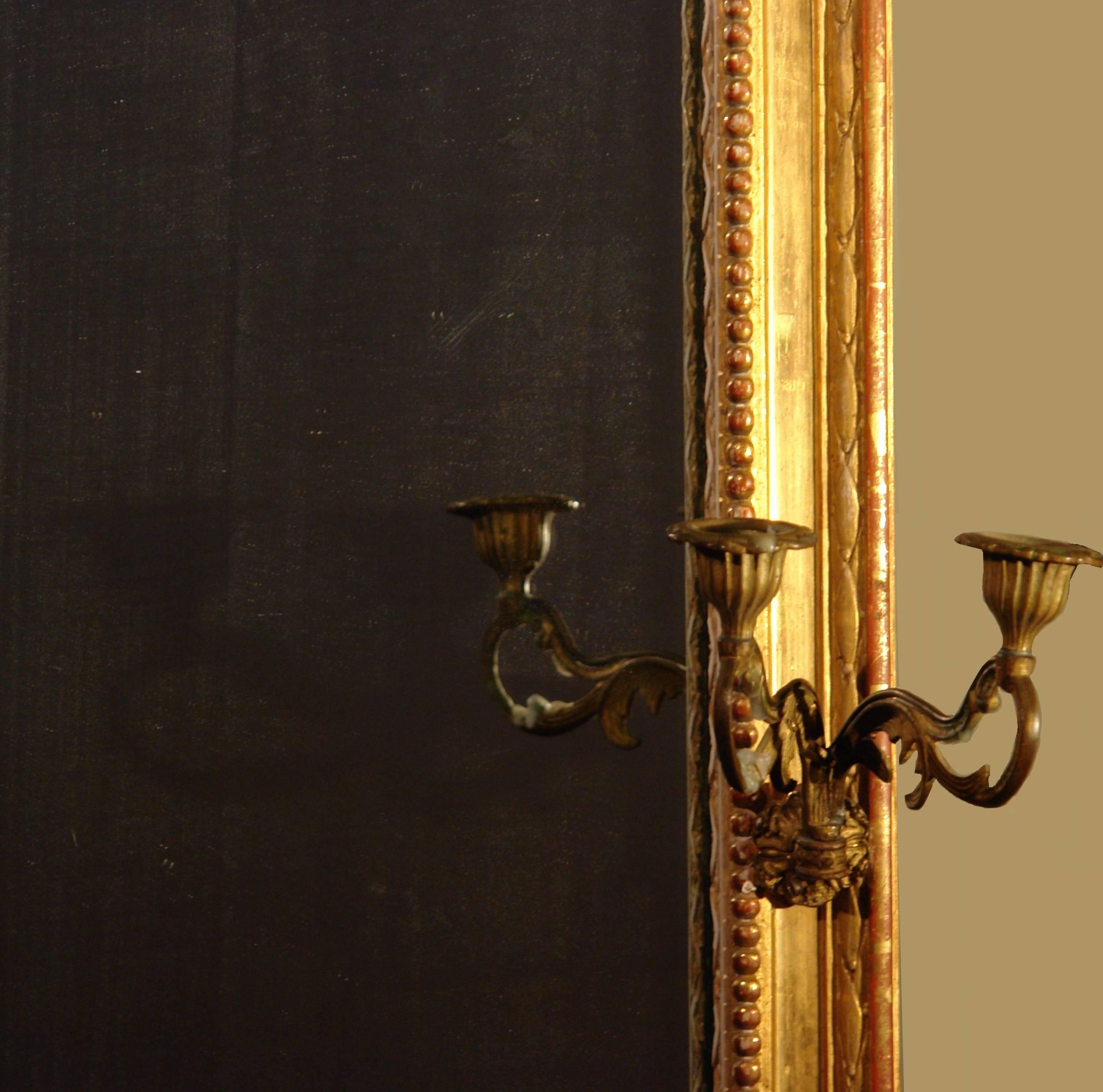 19th century French giltwood mirror retaining the original bronze sconces.
Beautiful water gilt frame and the original mercury glass mirror. Mercury glass provides a good reflective surface with a ghostly blue-silver glow. The back is the original