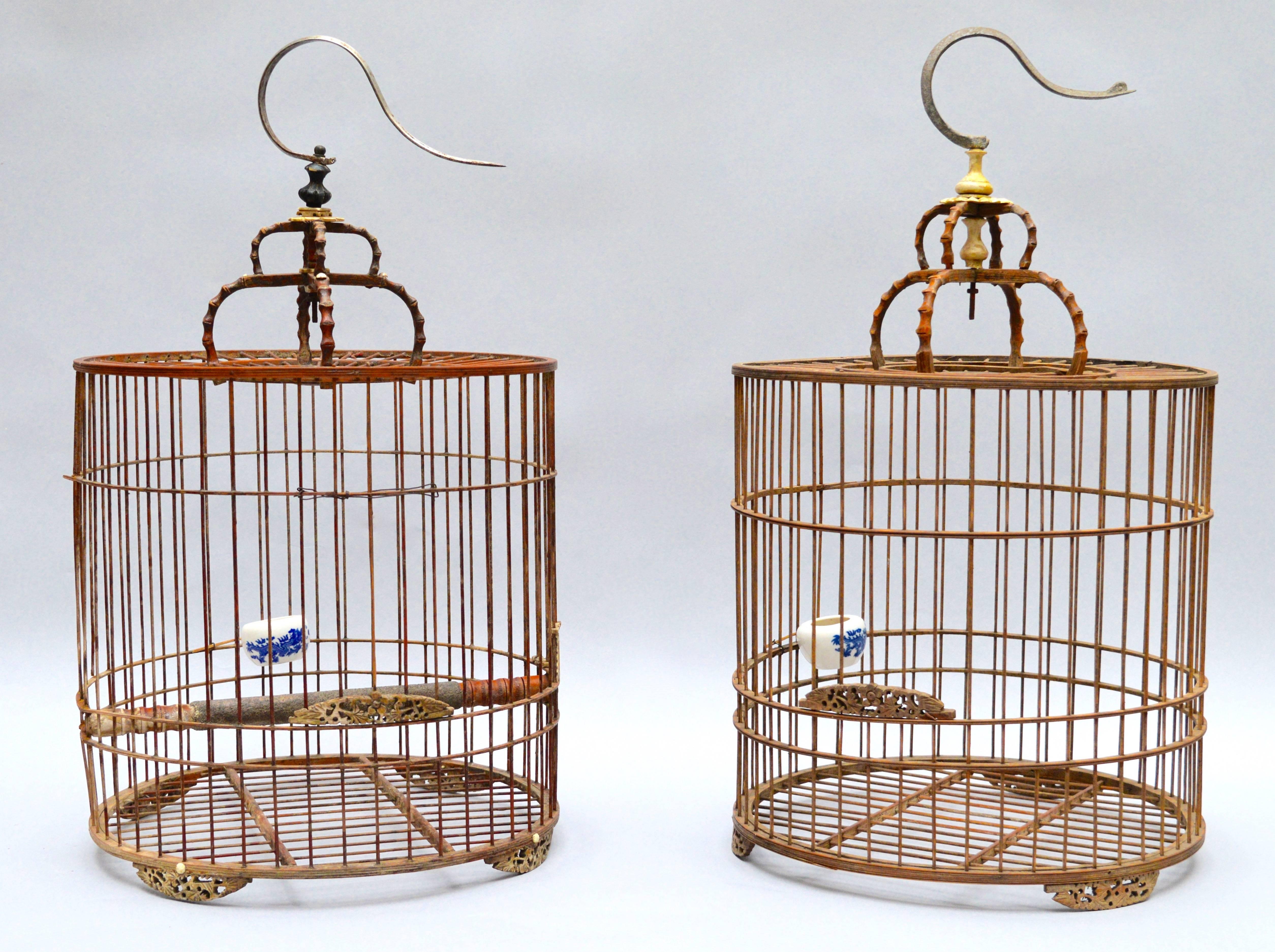 These Chinese birdcages are almost a perfectly matched pair except for the slightly different top finiels (which were replaced in the mid 20th century)
They are made of very light fine bamboo withcarved wood accents and metal hook handles. 
Men in