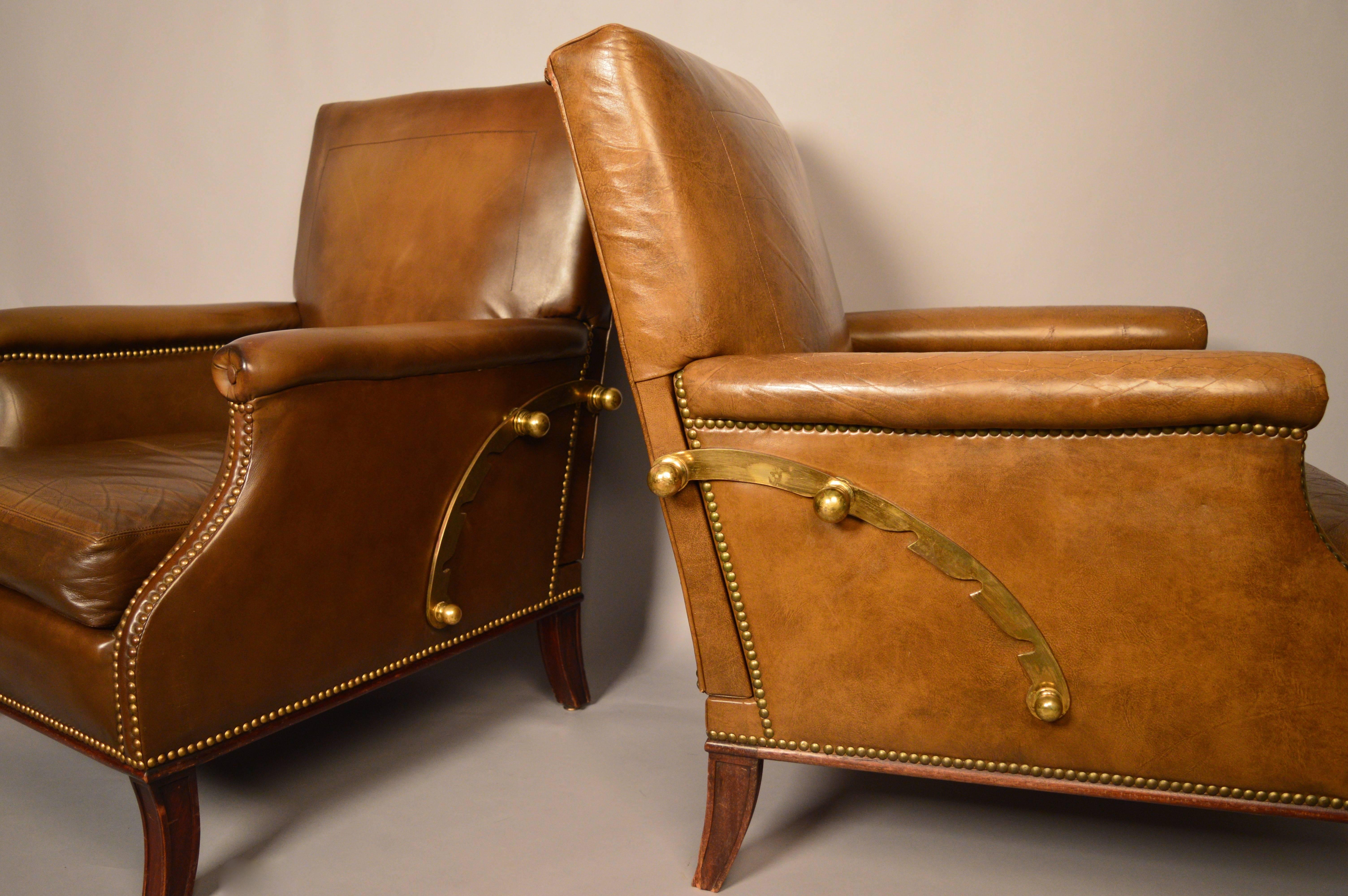 A pair of French neoclassical style armchairs with a brass mechanism that allows the back to recline in three positions.
Original brown leather upholstery and flared tapered mahogany legs.
