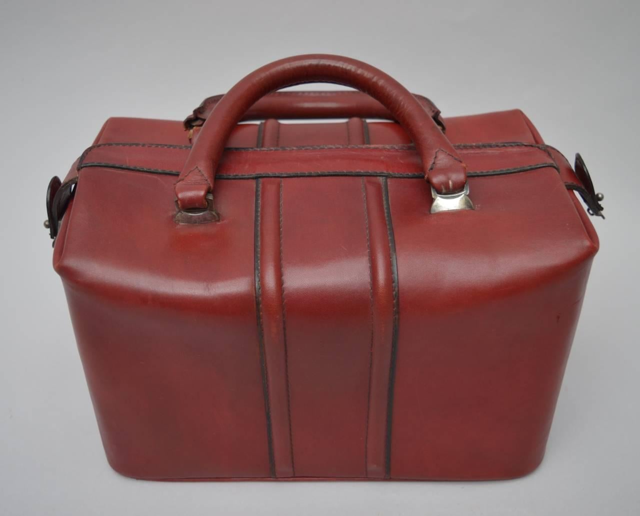 This vintage Italian leather satchel bag is in the perfect blood red color. The interior is lined in supple natural colored calfskin with a red leather strip to hold bottles and one zippered pocket. Still retains the 