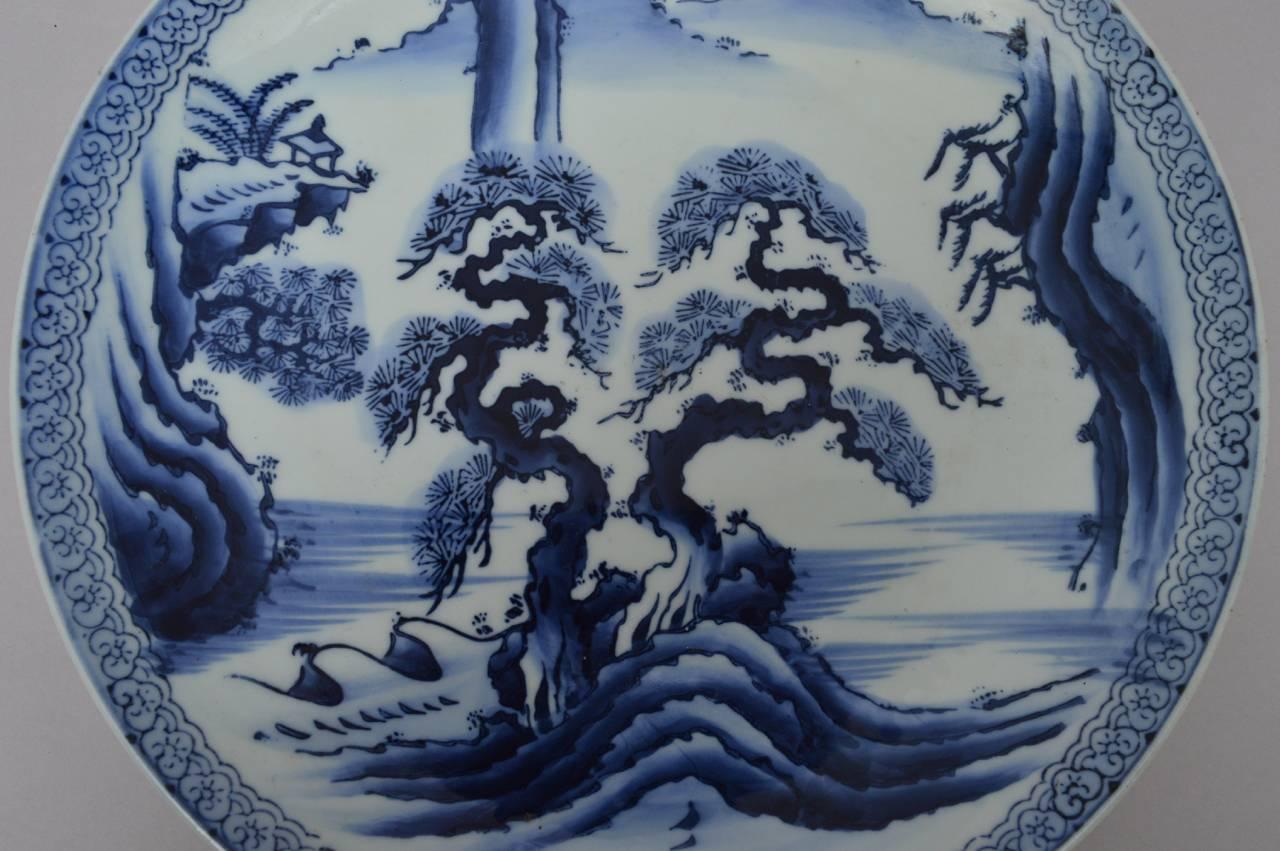 A Japanese Imari shallow bowl or charger with a beautifully mountain scene in blue and white. Excellent condition.